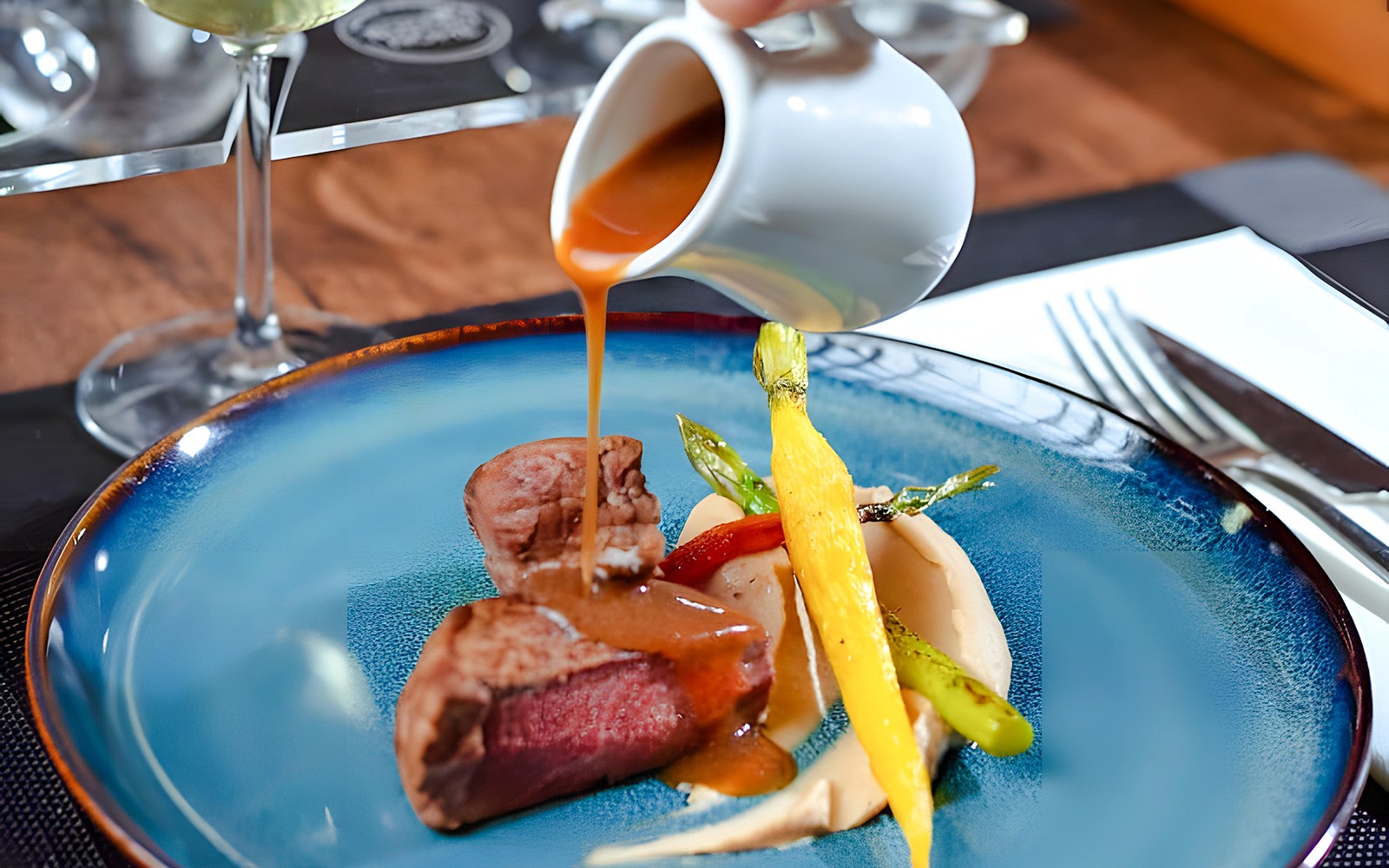 服务员在巴黎城市餐厅为牛排菜肴浇上酱汁。