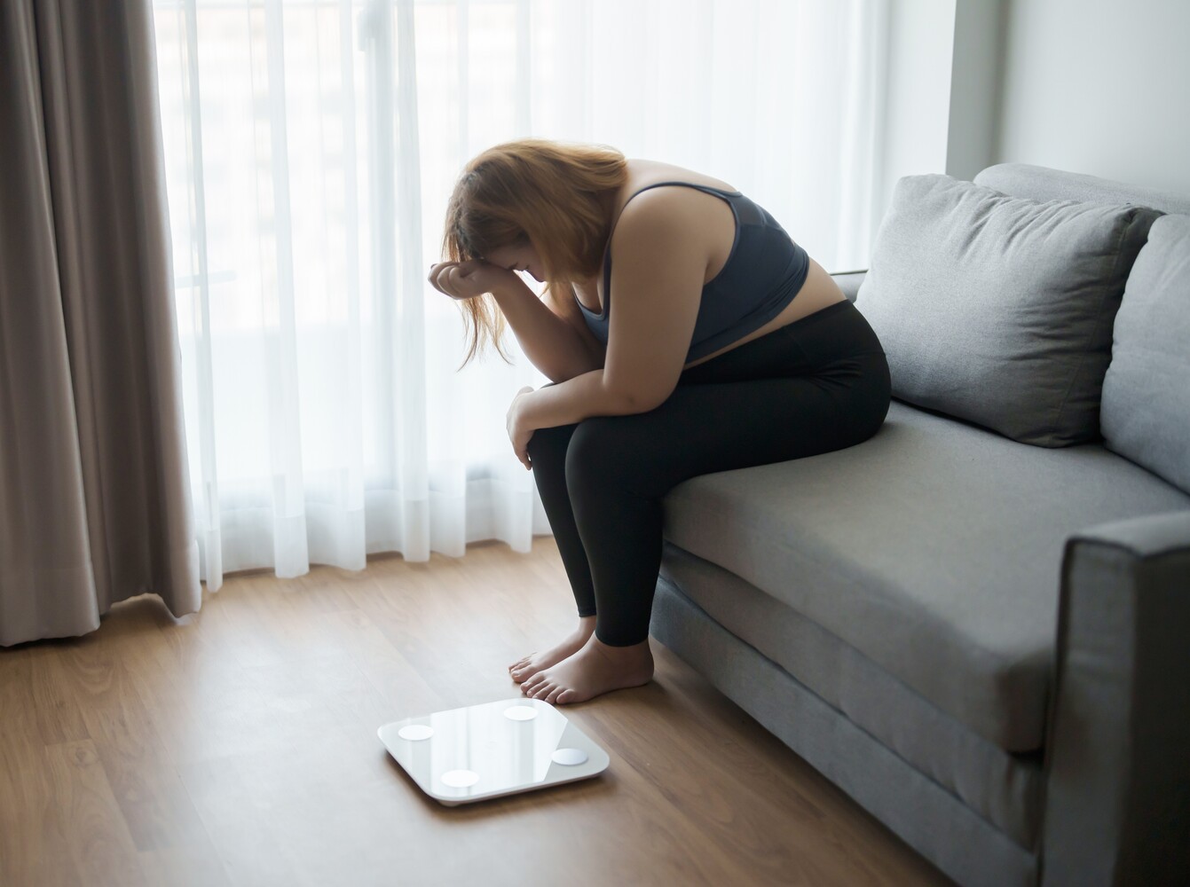 woman feeling defeated after not seeing a lower number on the scale from doing gym workouts to lose weight for beginners