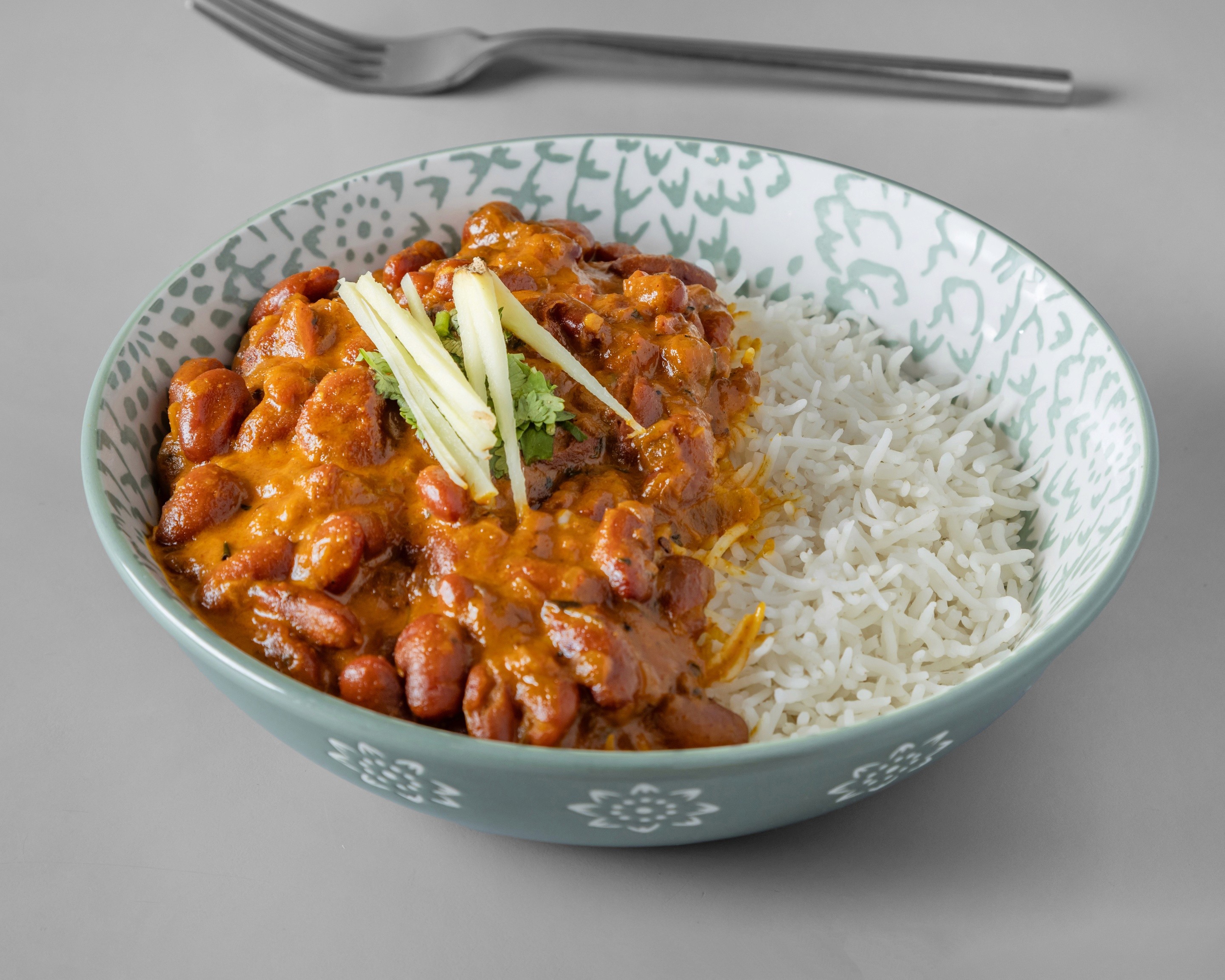A gourmet plate featuring a golden-brown, breaded chicken cordon bleu or roulade, sliced to reveal a yellow filling, served with a creamy sauce, roasted potato wedges, and a side of fresh salad greens on a wooden table.