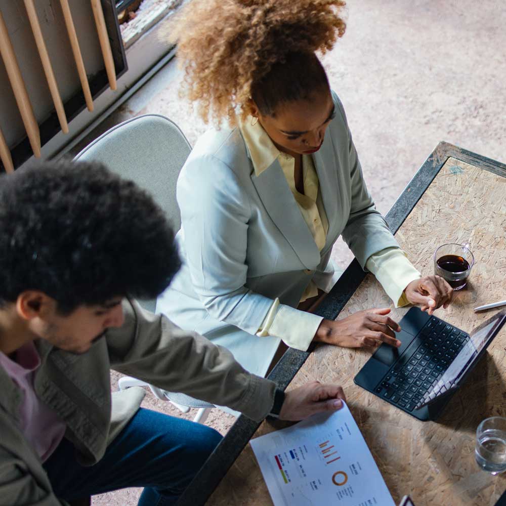 ein Bild von zwei Personen, die sich einen Arbeitsplatz mit zwei Laptops teilen