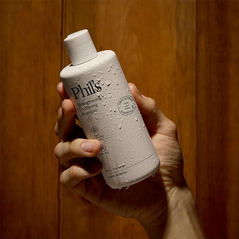 A model holding Phil's shampoo in a 300ml VIVOMER bottle. This microplastic-free container delivers the squeezable performance and barrier protection needed for daily haircare routines.
