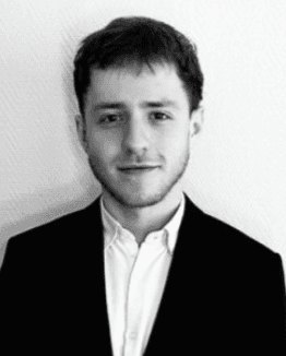 Close-up portrait of a freckled woman with soft pink hair and star earring, natural light, white tank top.