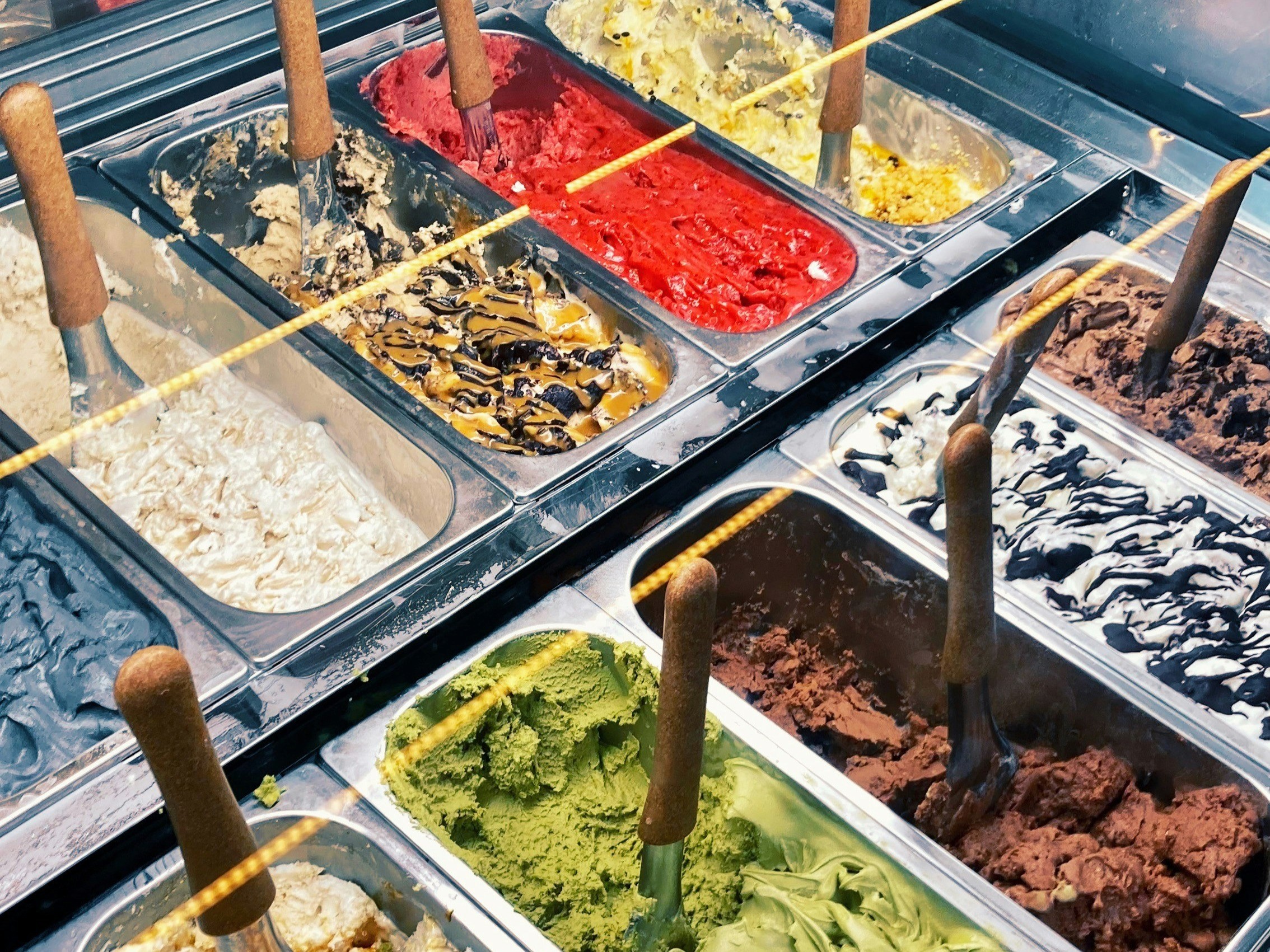 Gelato tray displays featuring a variety of colorful flavors.