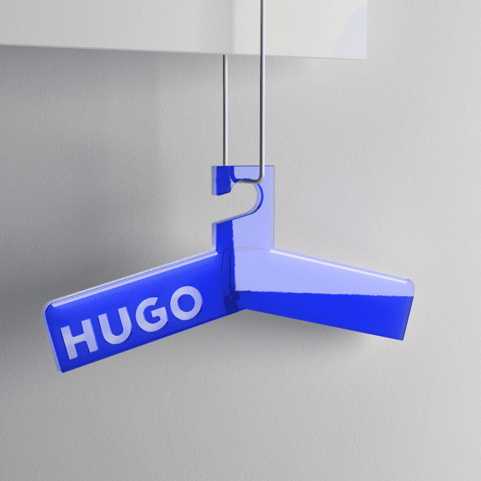 HUGO Brand Object – Y-förmiger Acryl-Kleiderbügel in Hugo-Blau mit eingelassener „HUGO"-Wortmarke, hängend an dünnem Draht vor hellgrauer Wand.