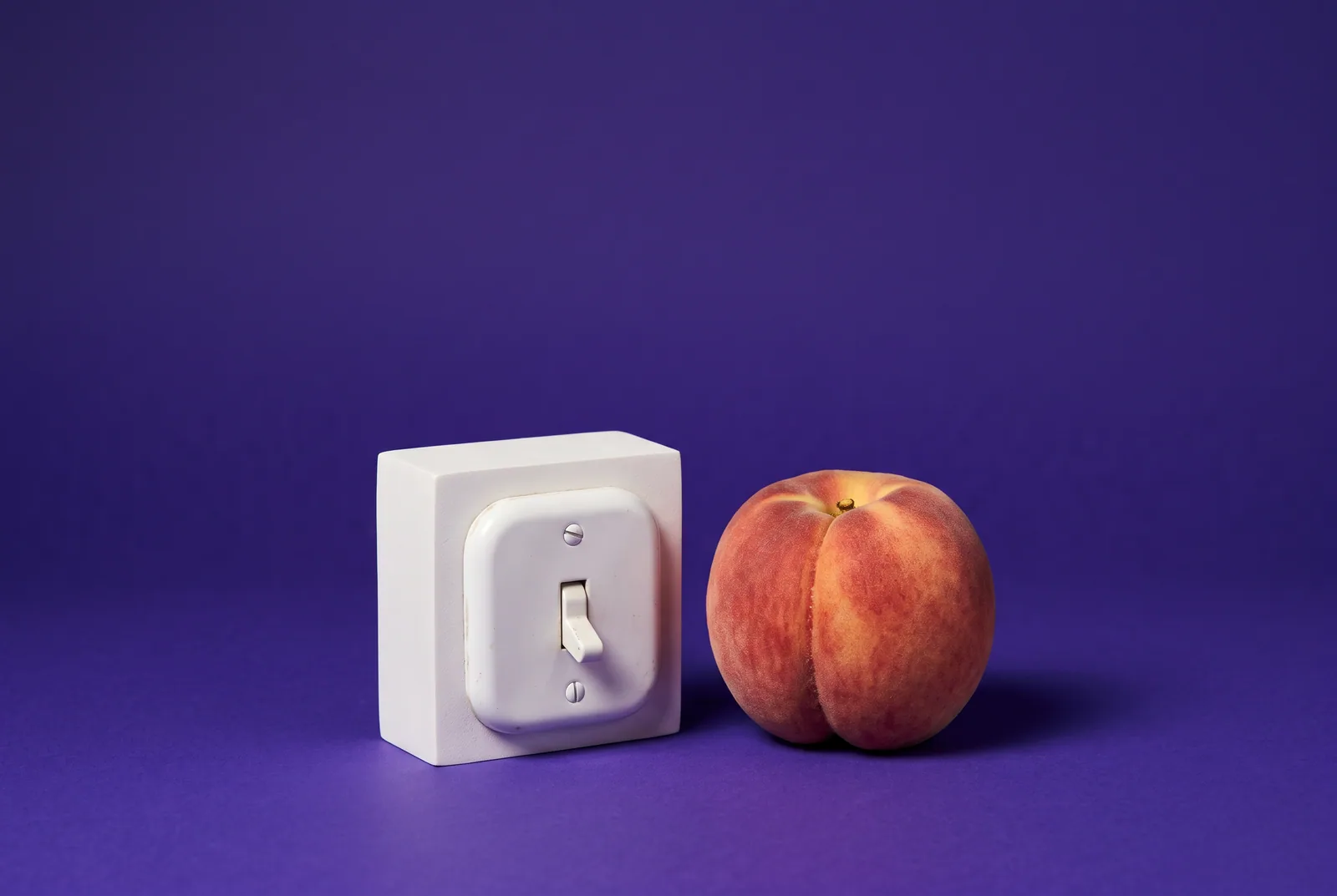 A white light switch flipped off beside a peach in shadow, turning off mature content to block NSFW on Reddit