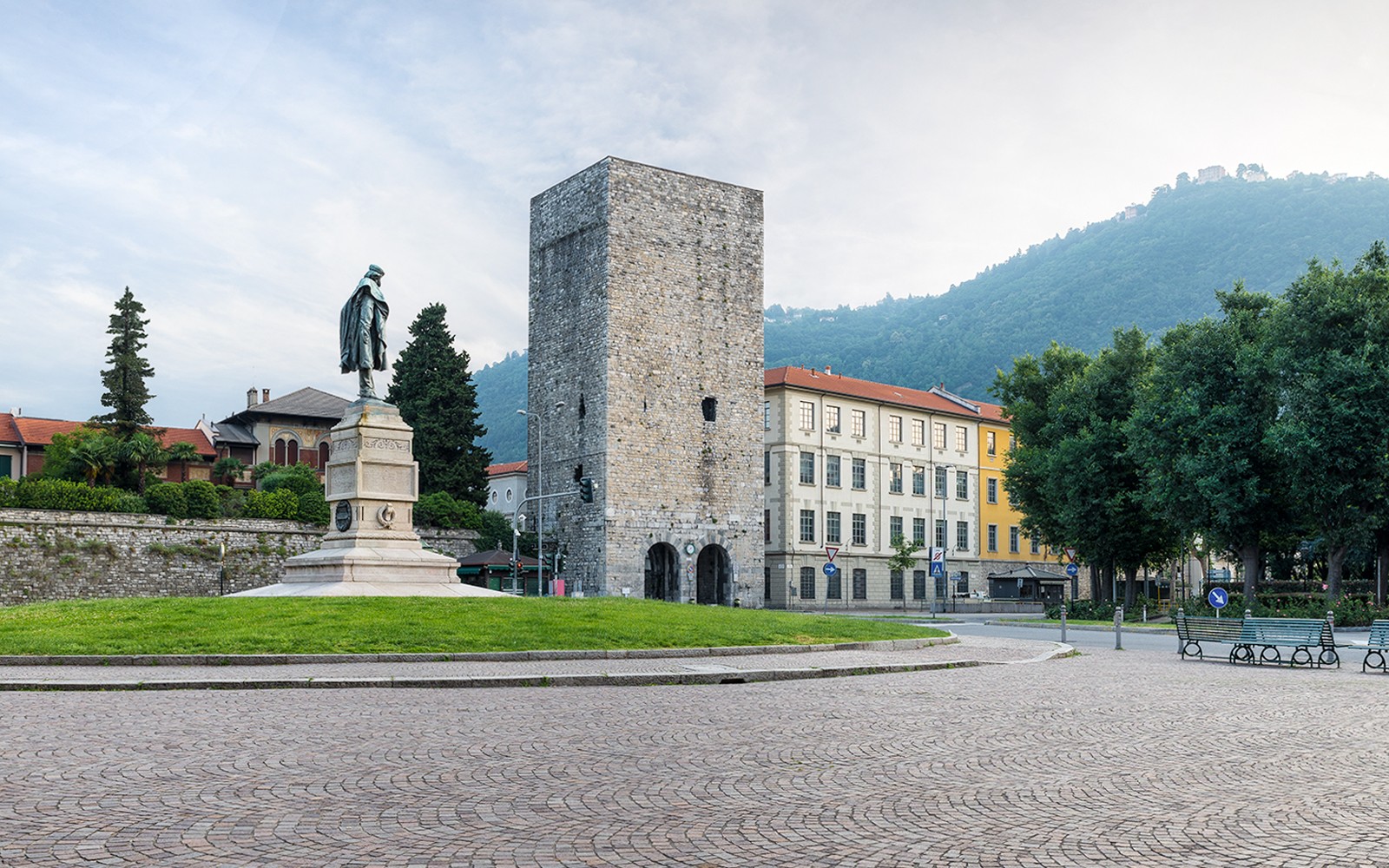 Porta Torre in Como, Italy, with a statue and surrounding buildings.