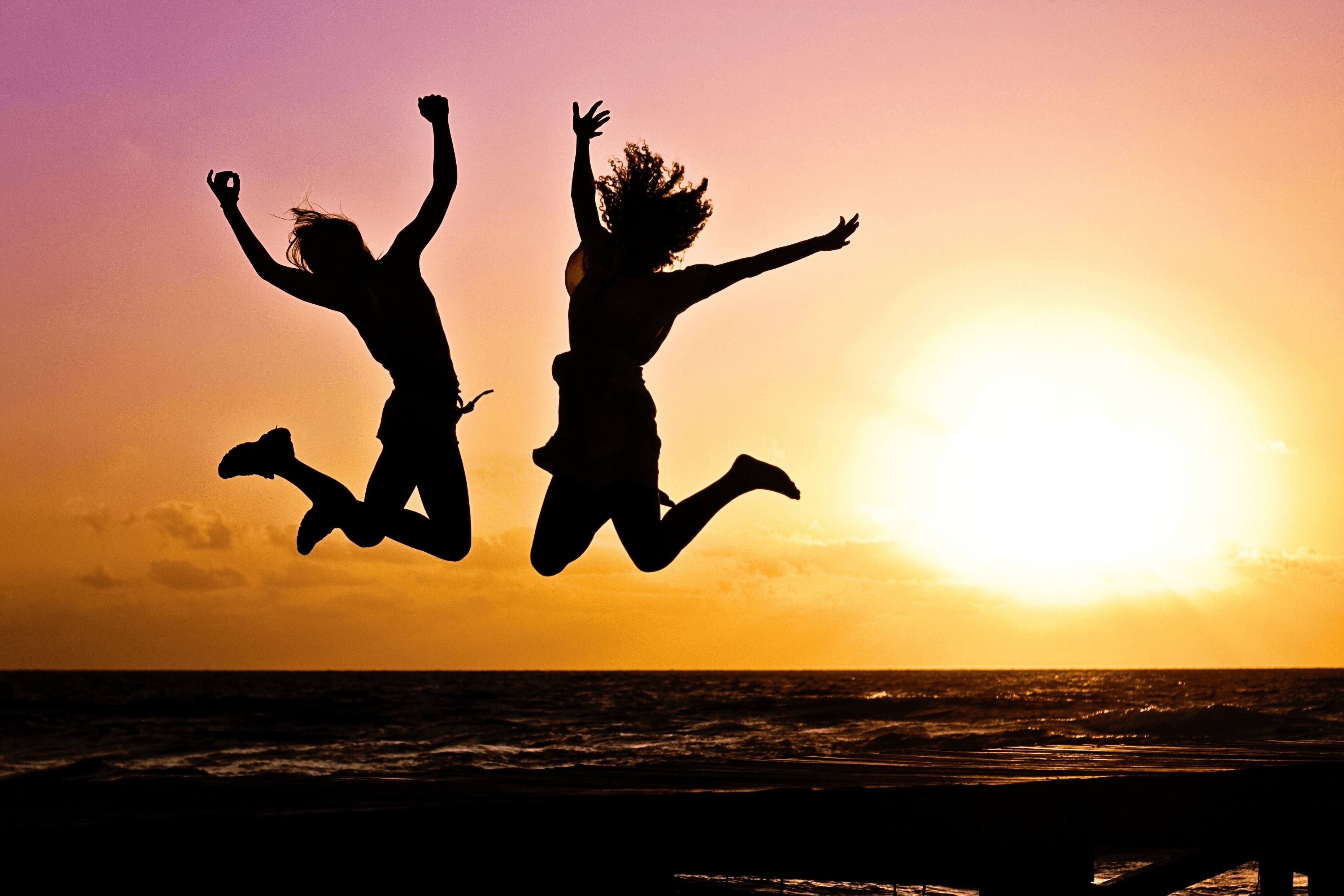 People jumping in the air at sunset.