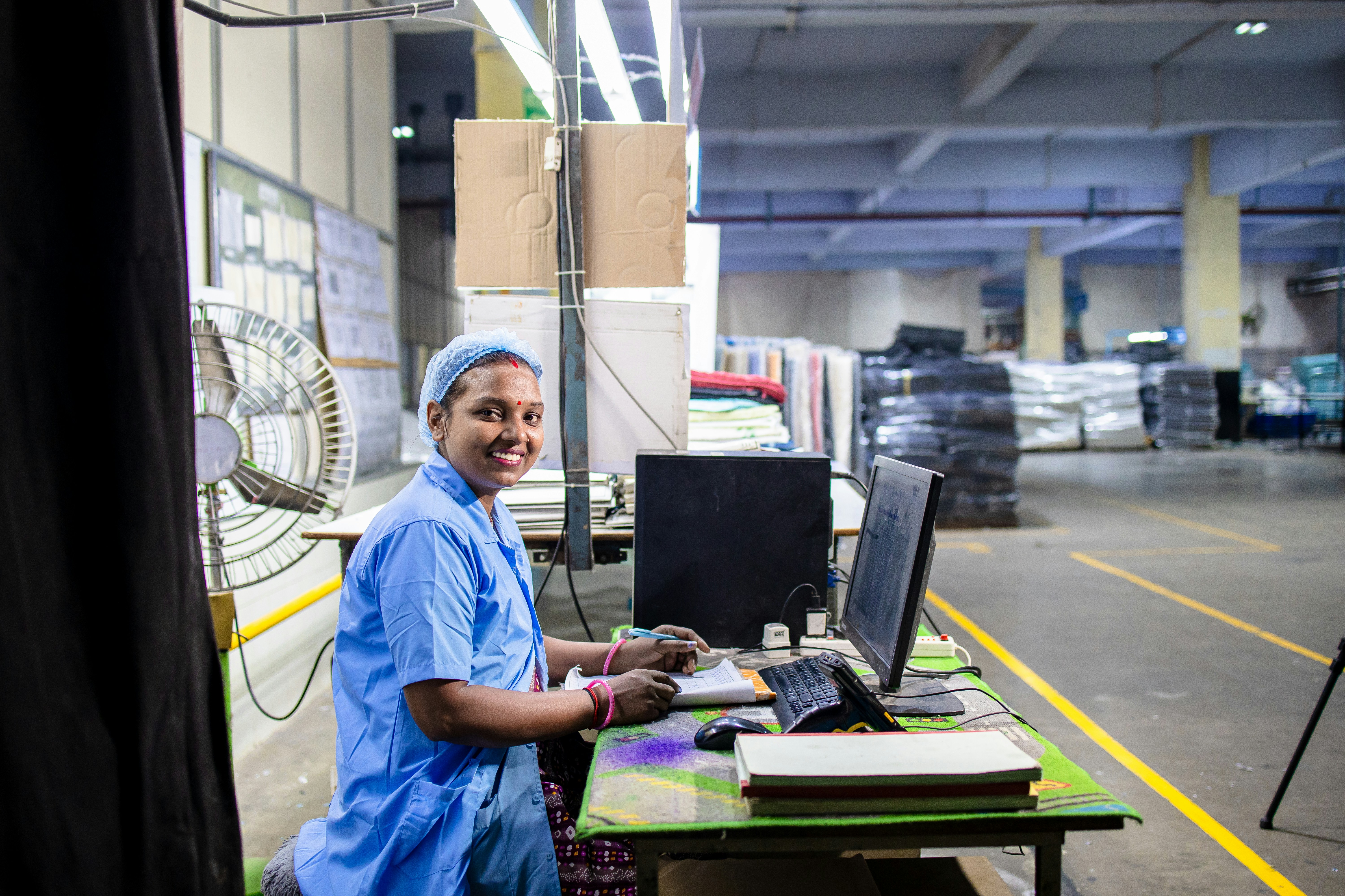 A woman works at a computer in a factory.
