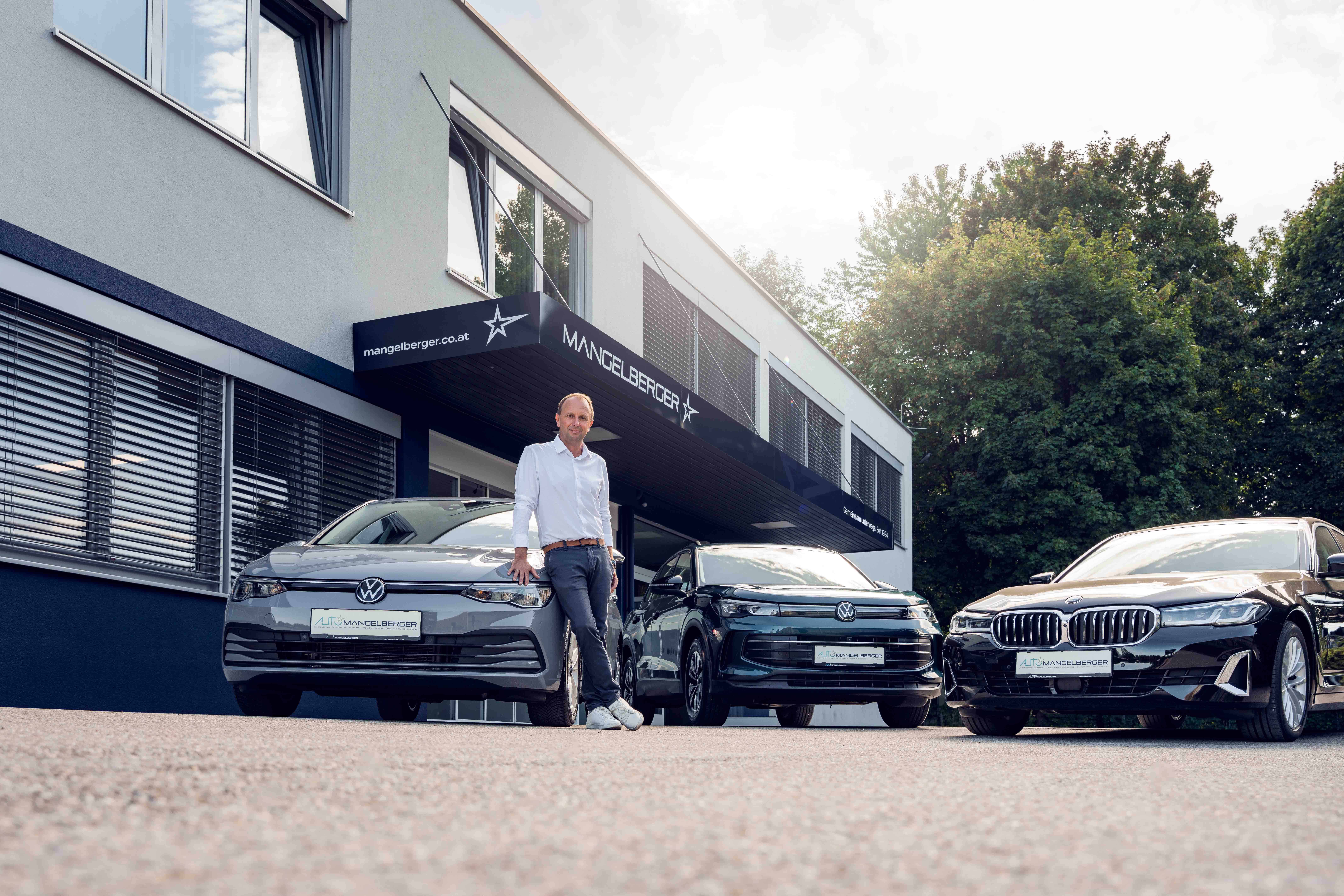 Neuer, dunkelblauer Audi A3 Sportback steht im Ausstellungsraum eines Autohauses mit moderner Einrichtung und Wandbildern.