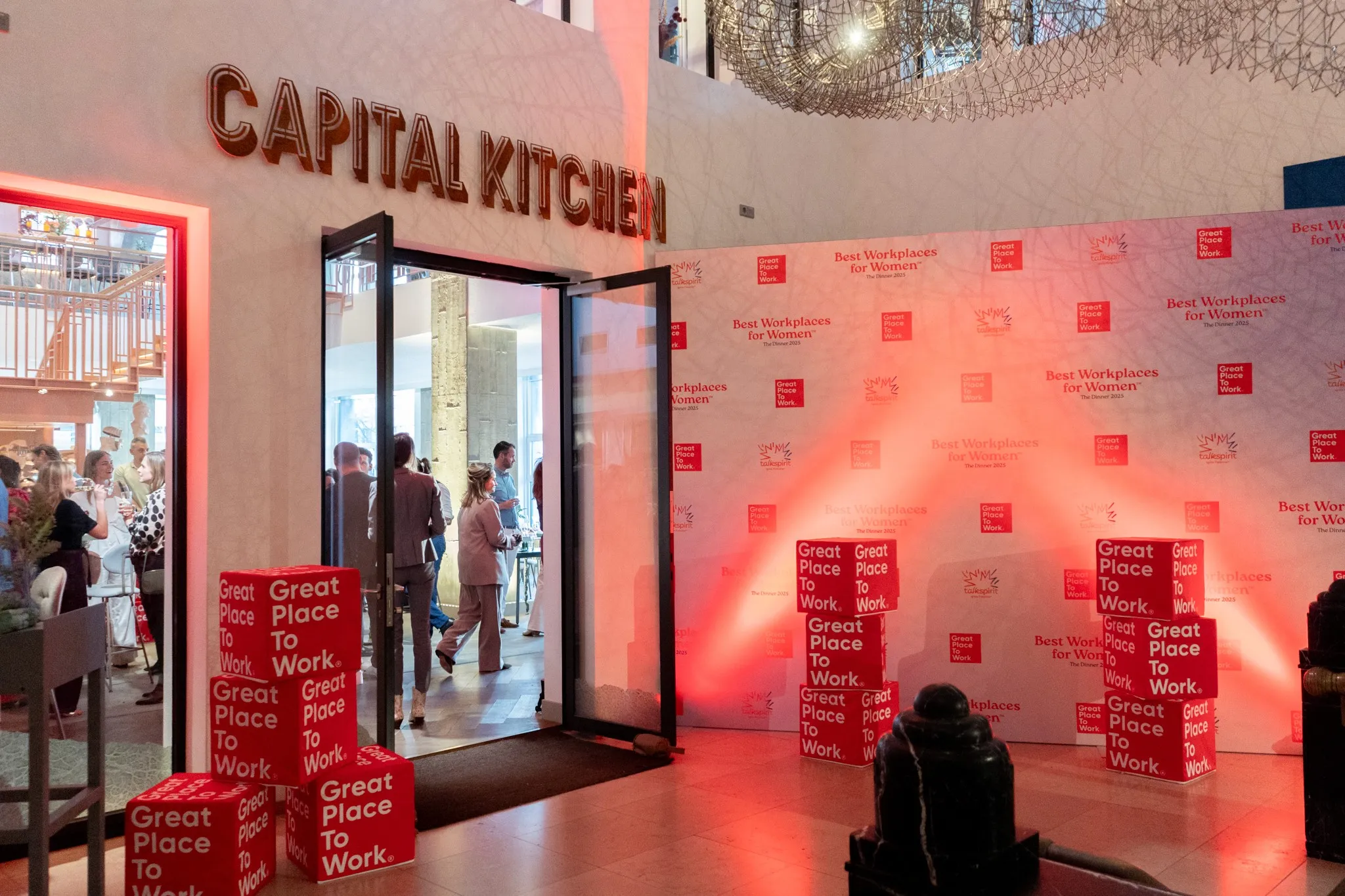 A storefront labeled "Capital Kitchen" with a vibrant, red backdrop and people in the entrance area.