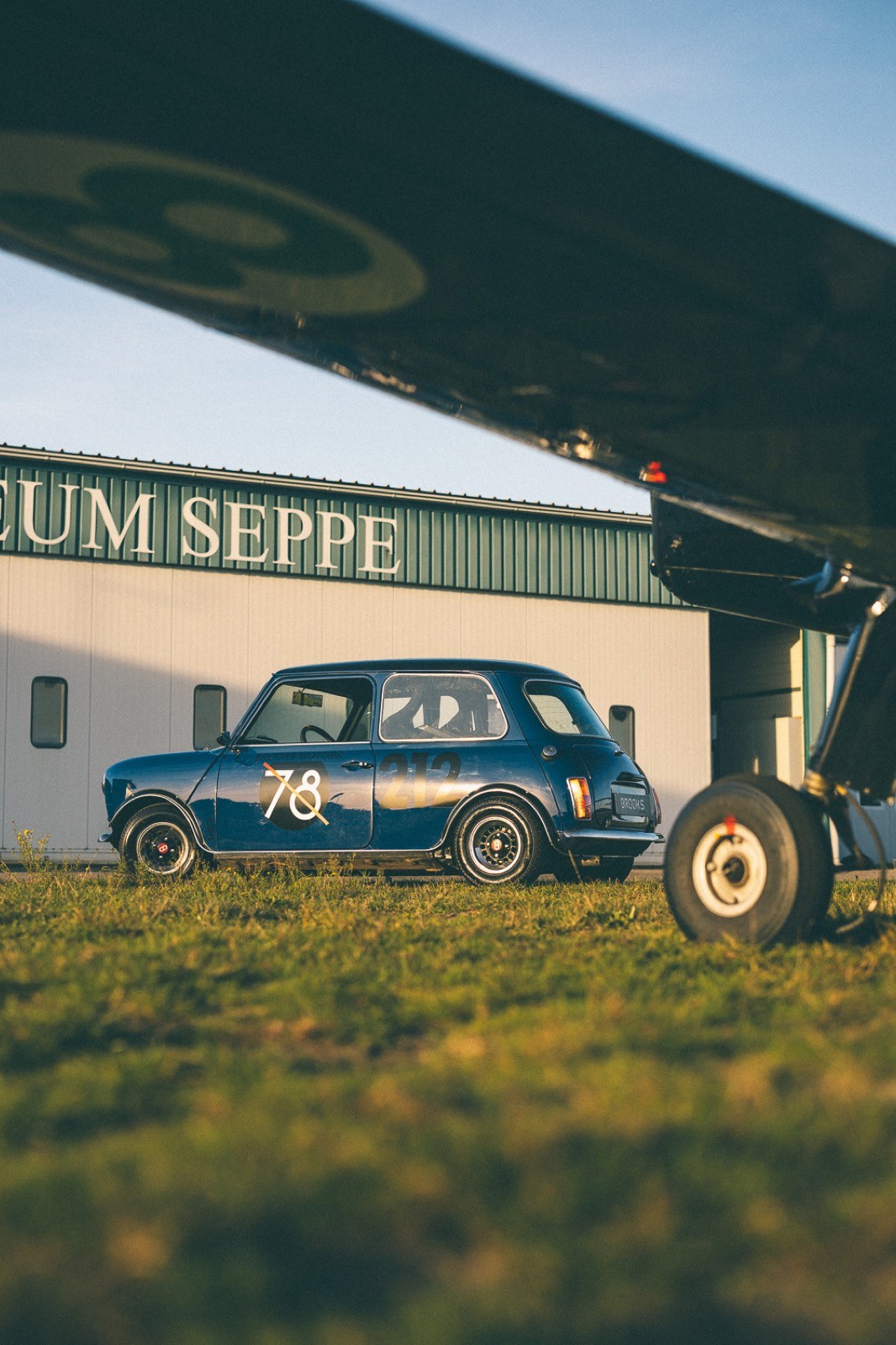 A small, green and black vehicle parked on a sandy surface, with a warm sunset lighting the scene.