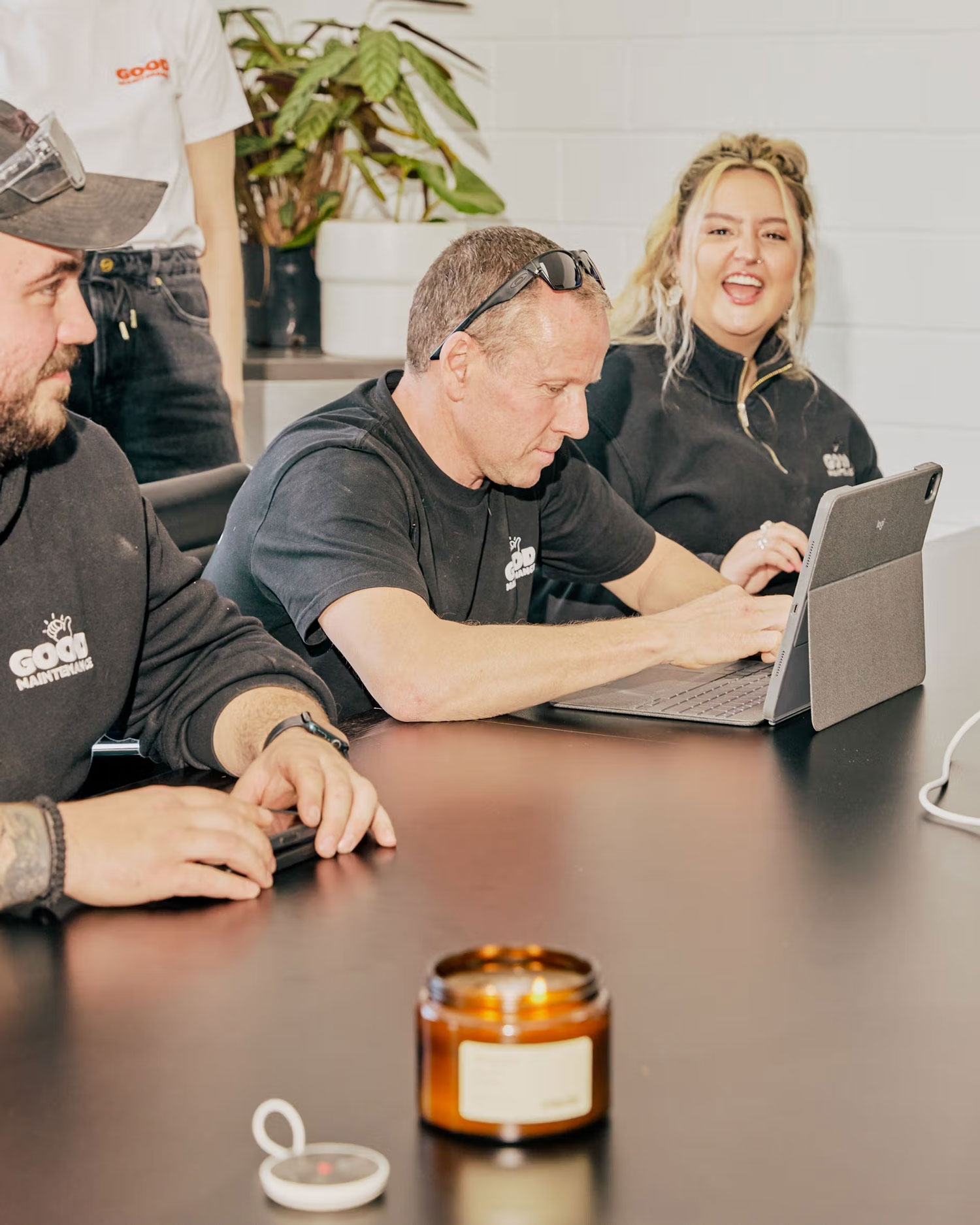 Good Maintenance team meeting around a table reviewing work on a tablet.