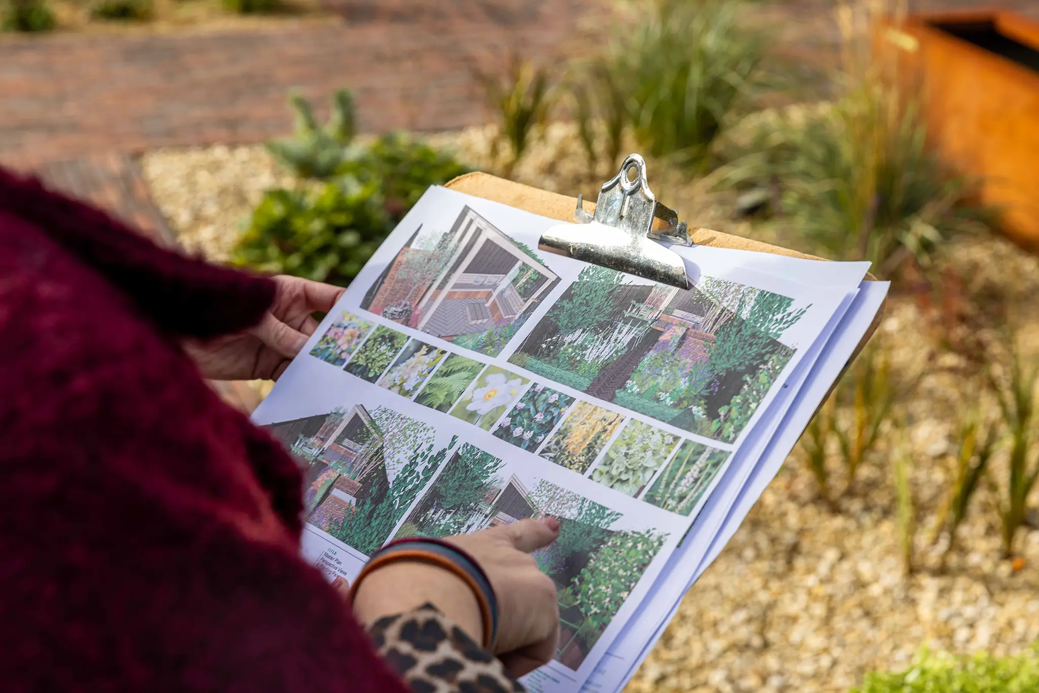 A person reads a magazine outdoors, surrounded by grass and plants, with vibrant colors in the background.