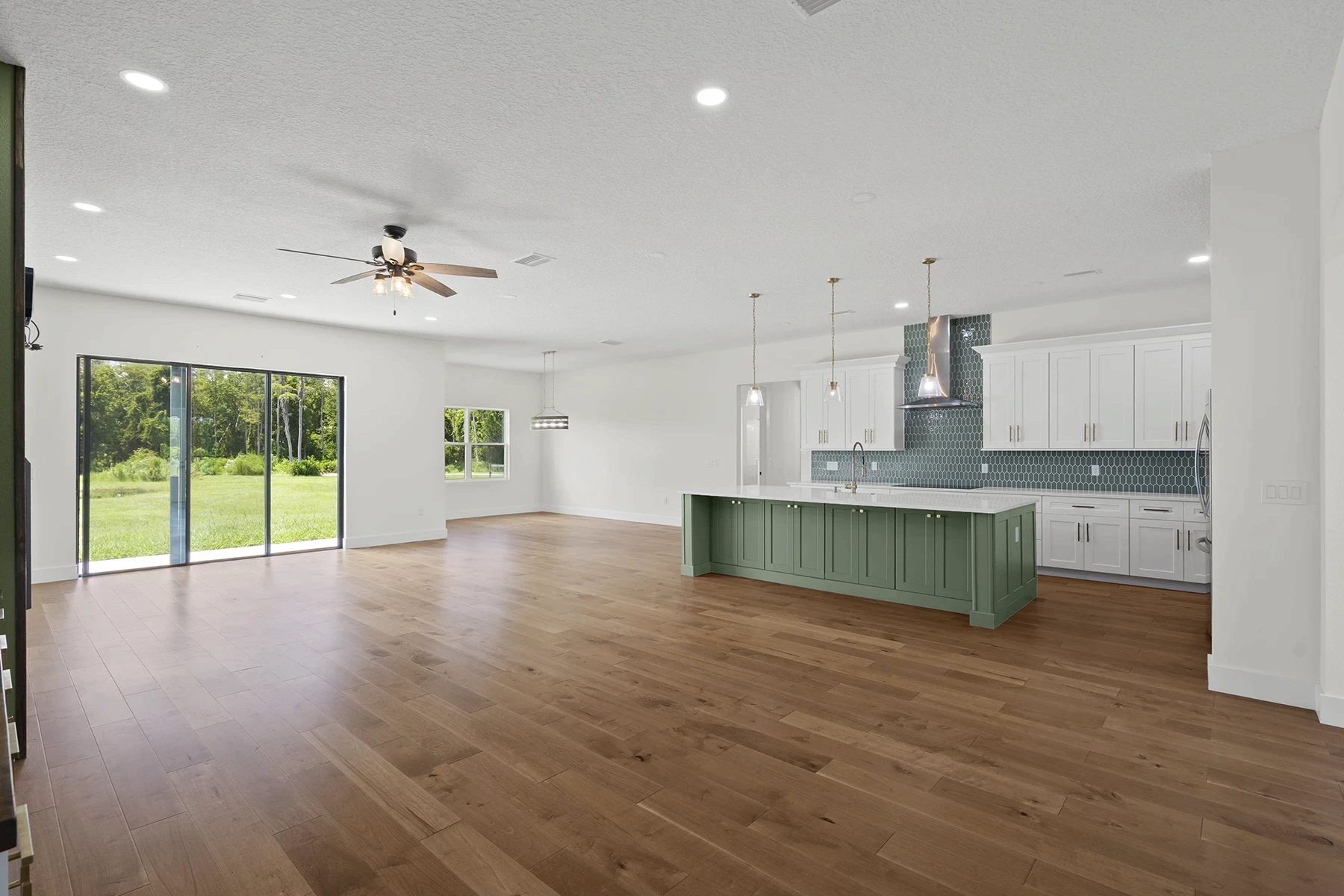 Open-concept living space with a green kitchen island, white cabinetry and hardwood floors in a St. Cloud modern farmhouse