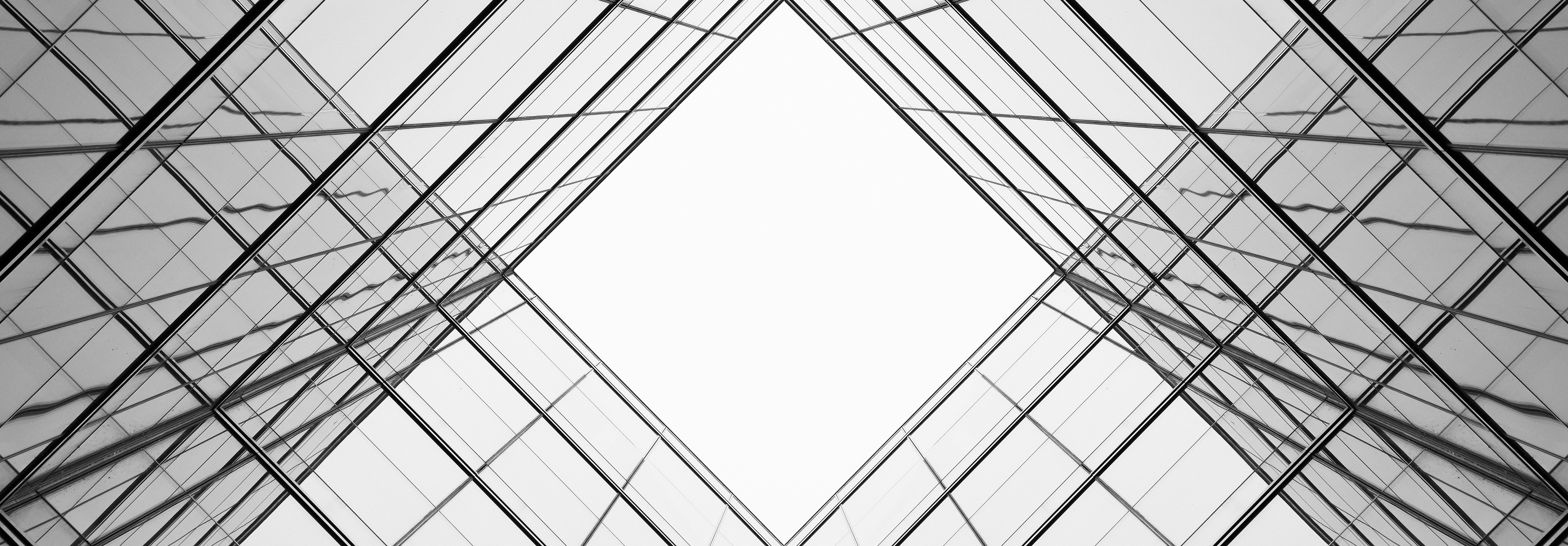 Abstract, symmetrical glass architecture forming a diamond shape, used as a backdrop for the corporate value “Integrity,” conveying transparency, structure, and ethical responsibility in decision-making.