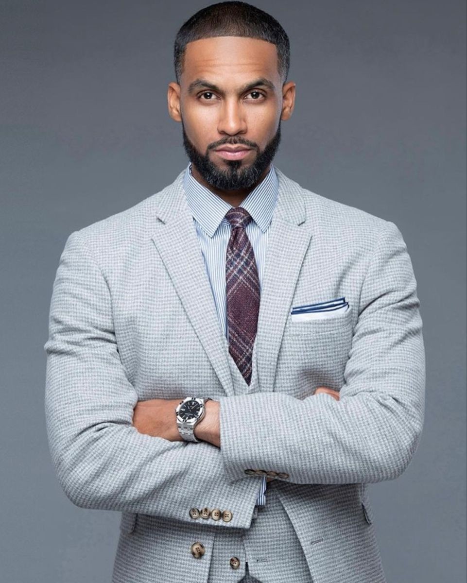 Close-up portrait of a blonde woman in translucent pink glasses and a white shirt on a soft blue background.