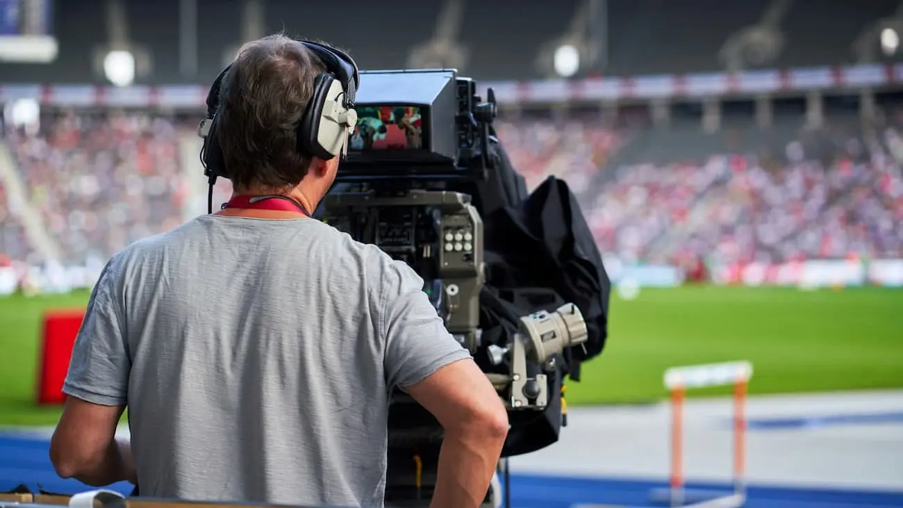 A cameraman capturing live football action during a Bundesliga match, showcasing the dynamic and globally popular nature of German football leagues, poised for digital expansion and international market presence.