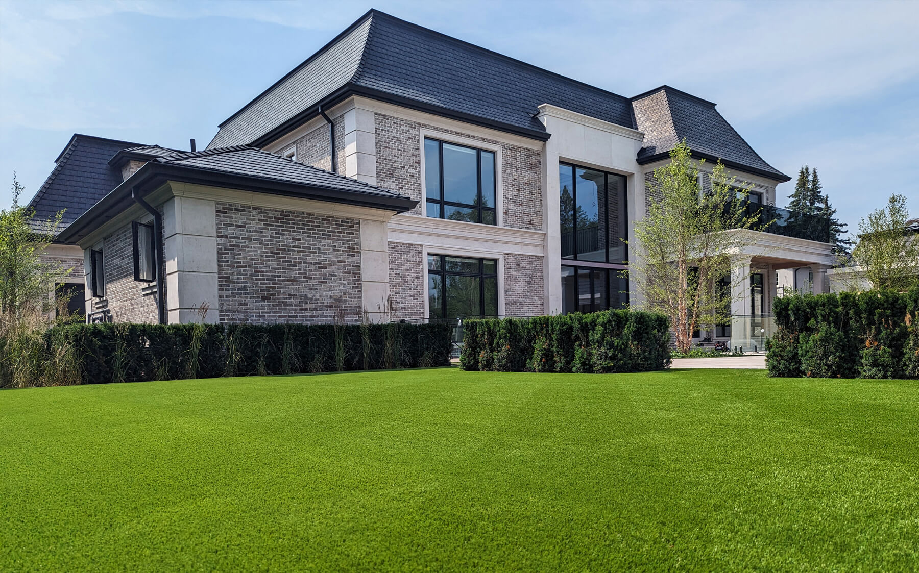 A beautiful brick home in King City showcasing a Saratoga 60 artificial turf installation by AGL Grass North.