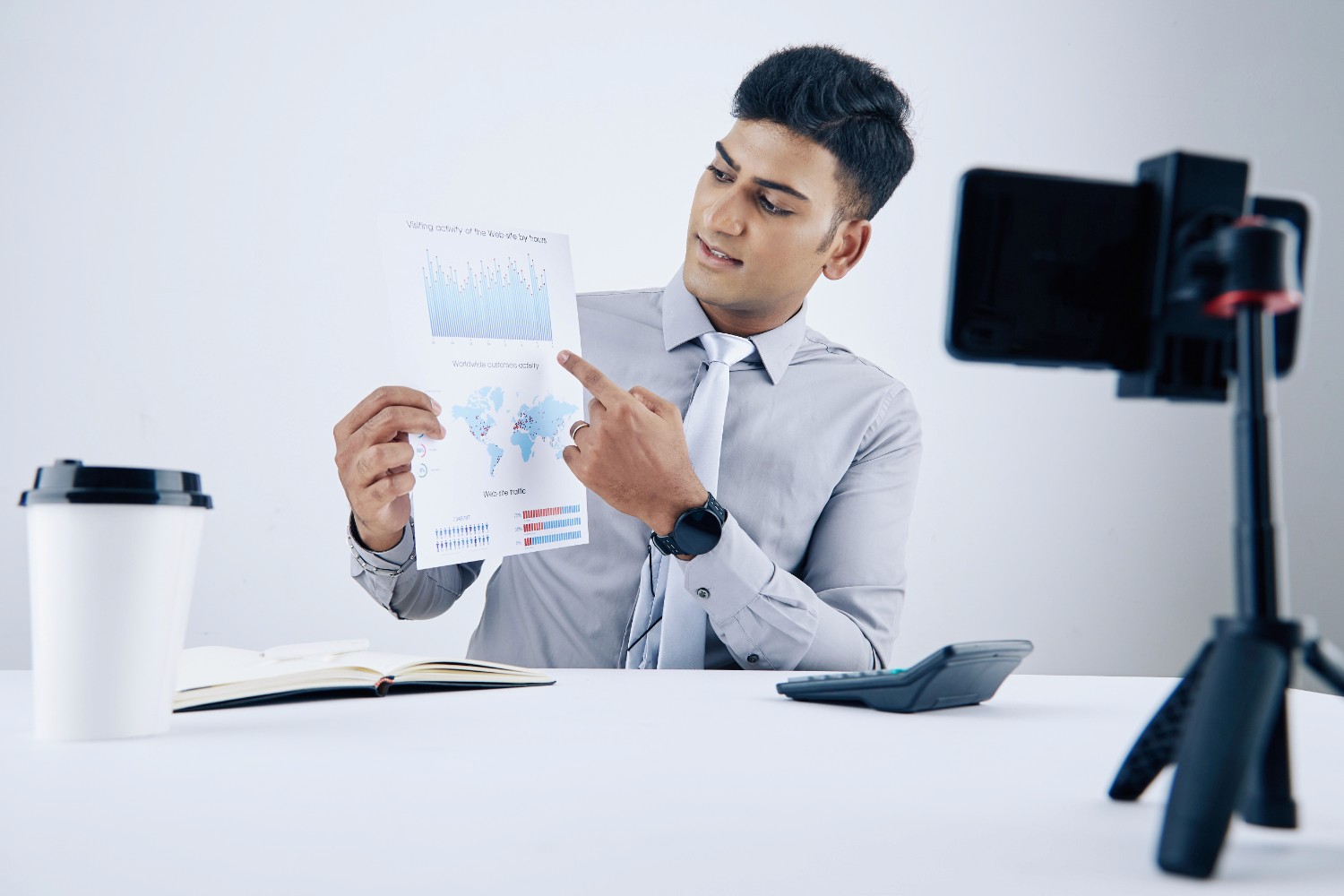 A man in a business suit stands confidently, holding a piece of paper in his right hand, ready for a presentation.