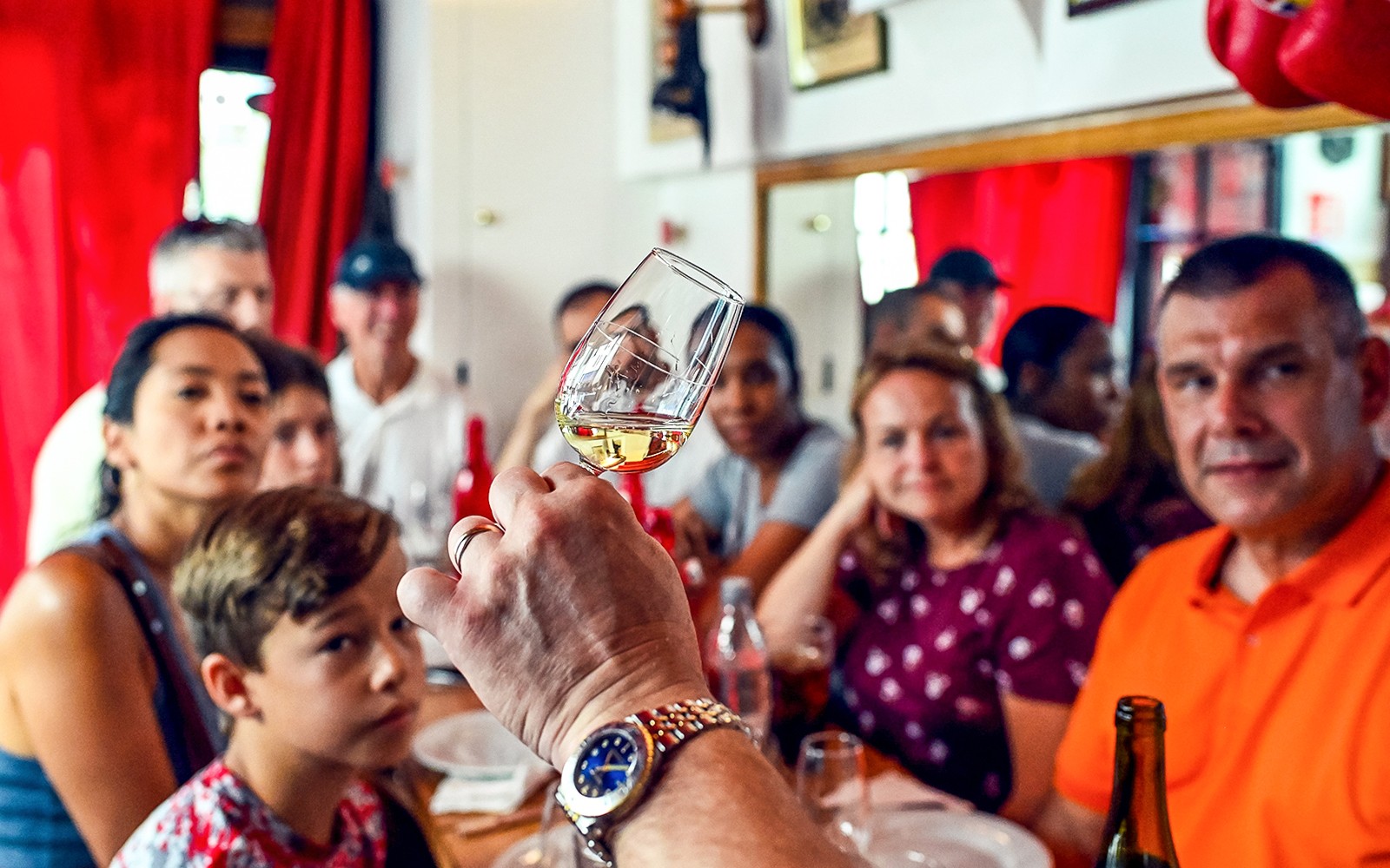在巴黎圣日耳曼美食之旅中，参加品鉴会，与一群人在一边观察酒杯。