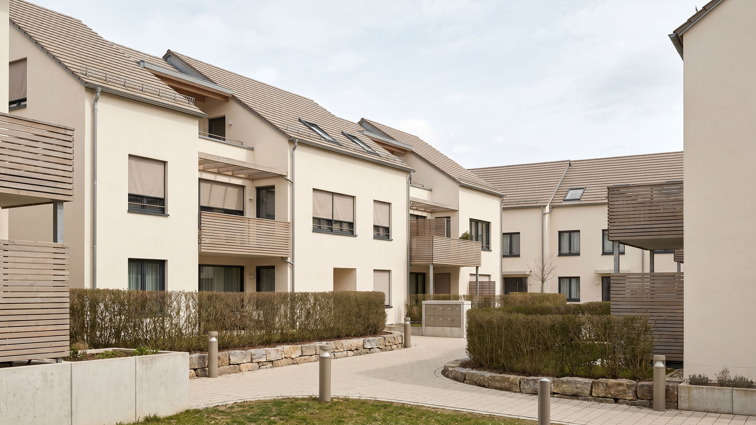 Mehrfamilienhäuser einer Wohnsiedlung mit begrünten Innenhöfen und Holzbalkonen