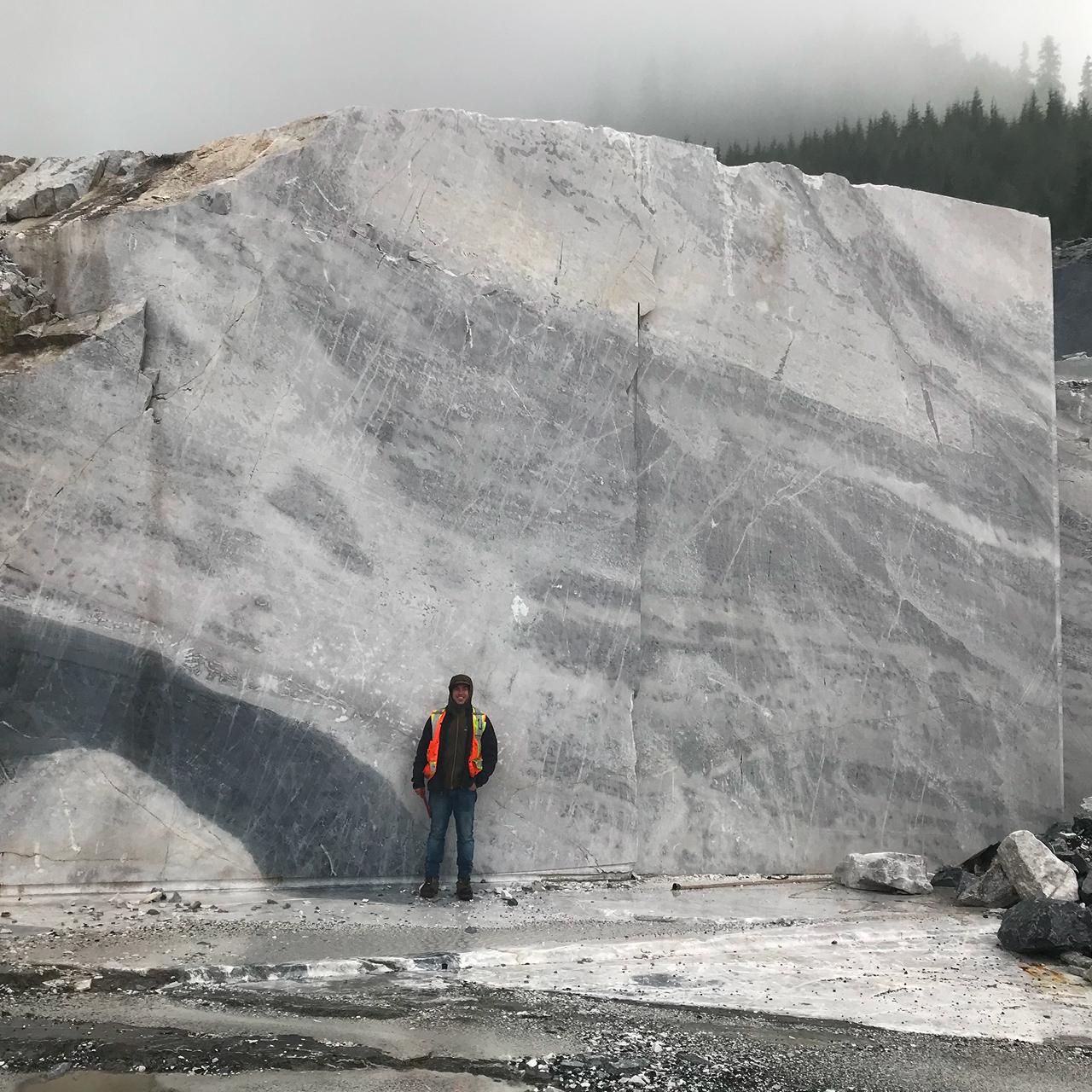 Engineer standing before massive ice wall during winter site assessment at Callache Quarry reclamation project in Tahsis