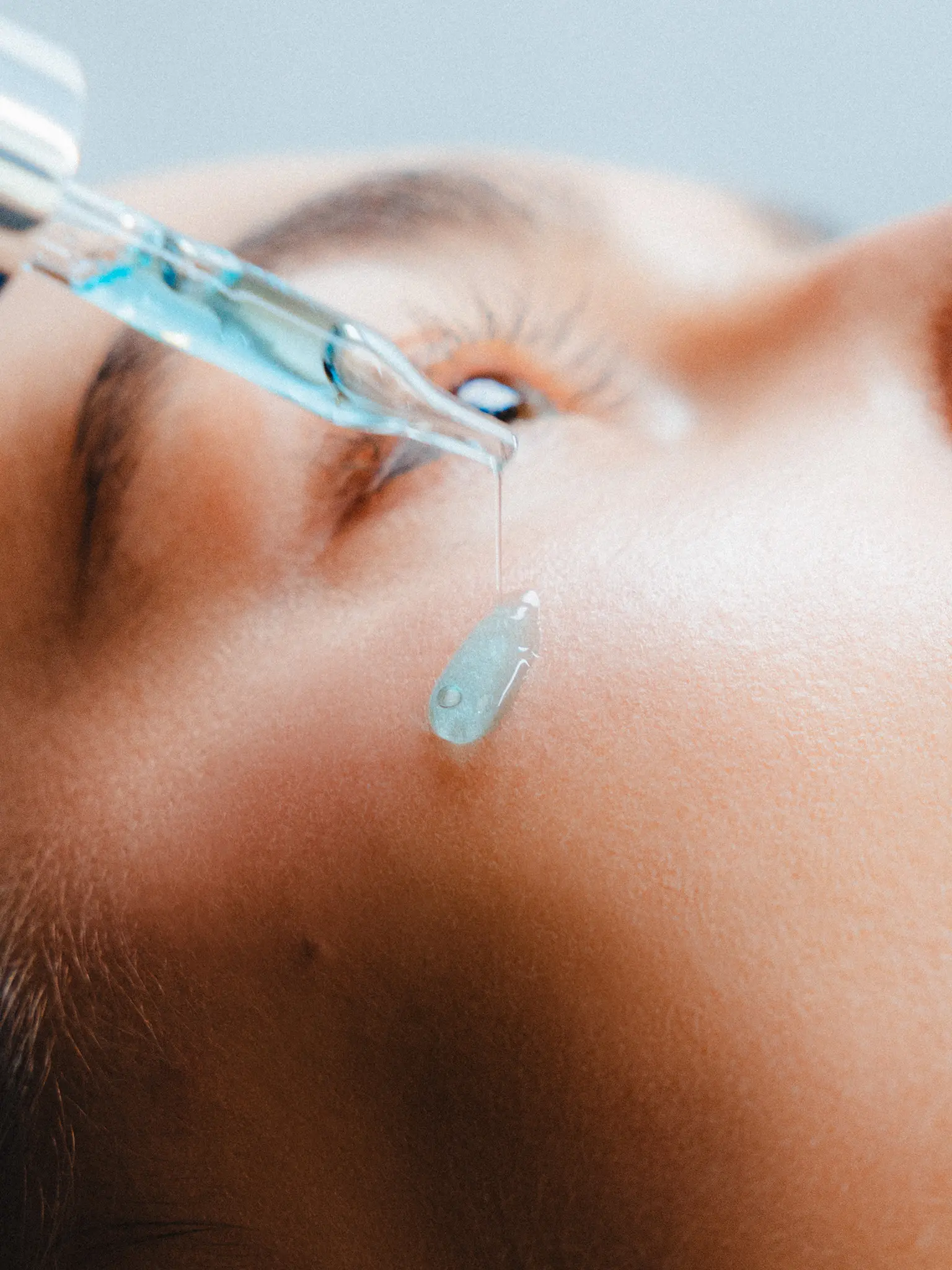 Facial skincare routine with serum dropper applying hydrating serum on skin.