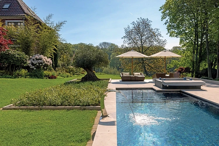 Üppige Gartenanlage mit Poolrand, Liegestühlen und Sonnenschirmen