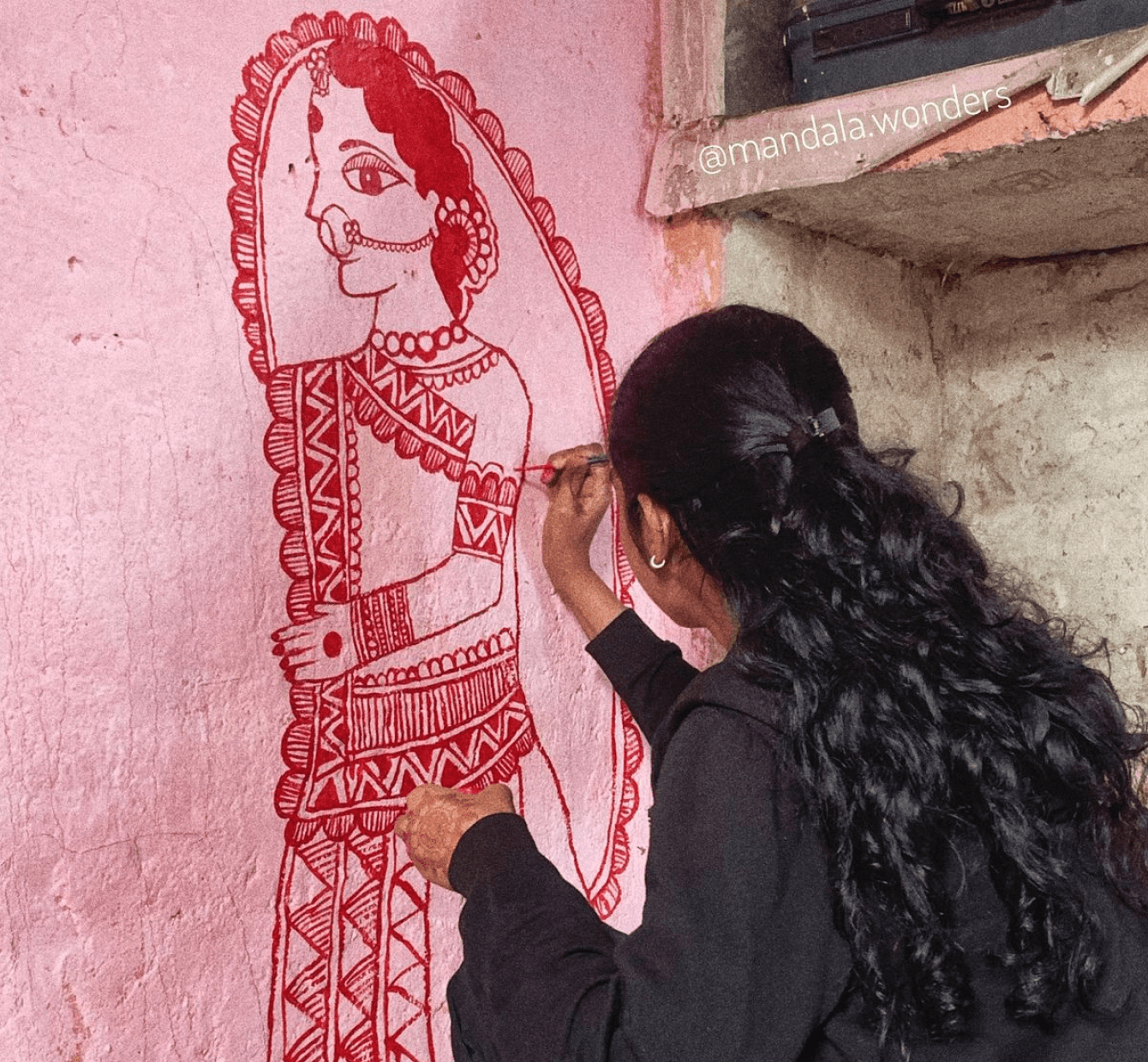 An Indian woman drawing Mithila painting on the wall
