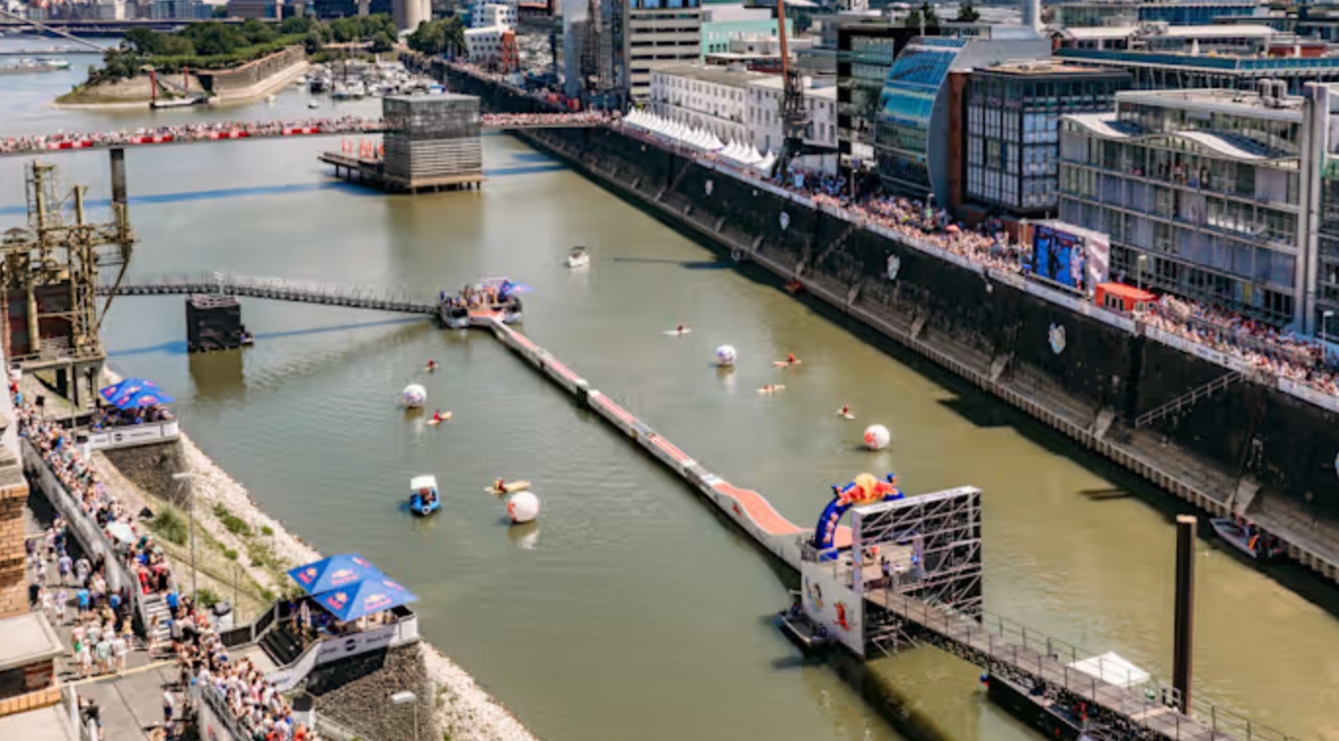 Großes Outdoor-Event-Setup mit Wasserbecken, Rampen und Zuschauern.