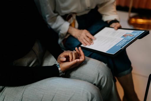 The image depicts a professional setting where important documentation on a clipboard is being reviewed or discussed.