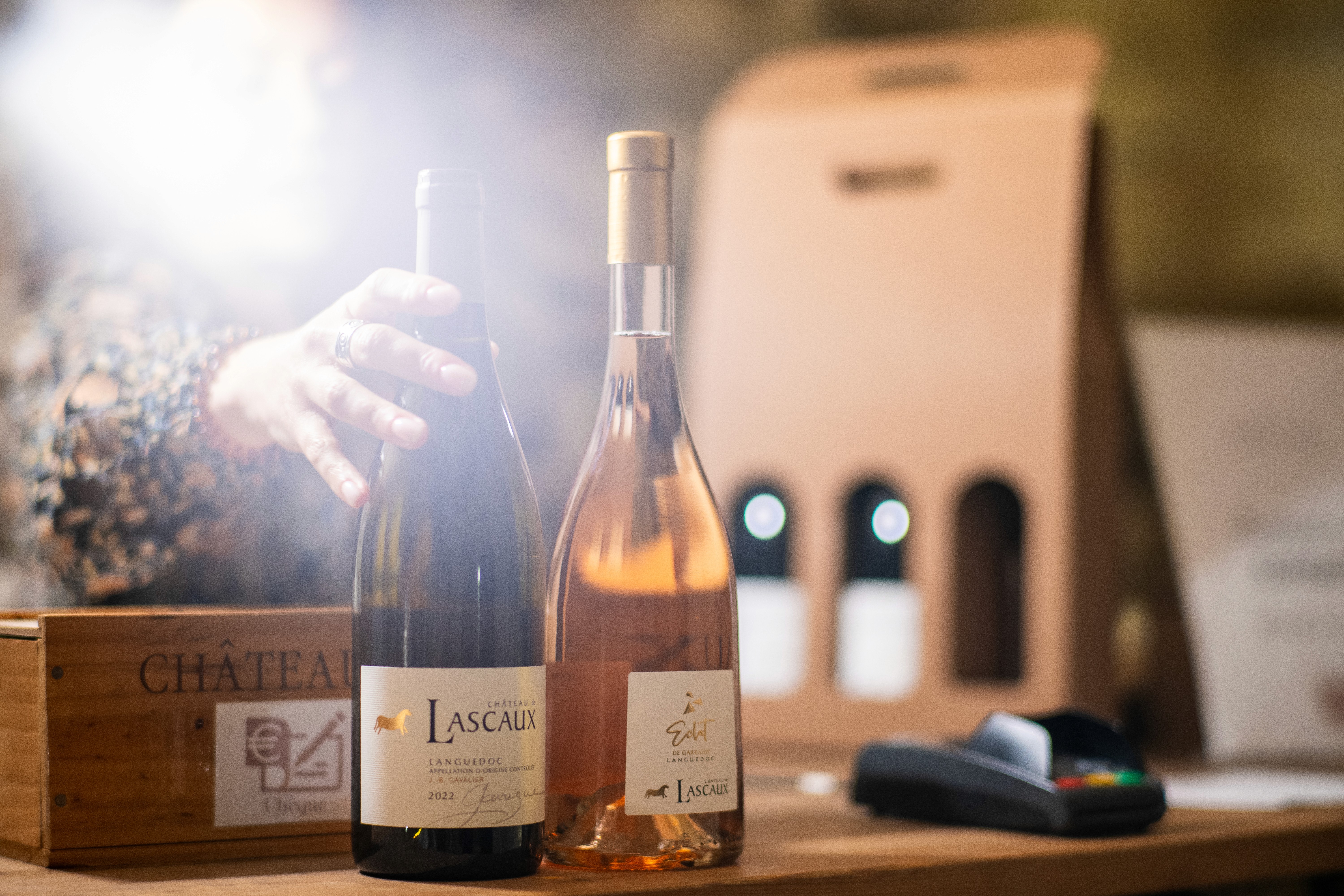 A woman selling wine bottles at a French vineyard, with soft lense flare