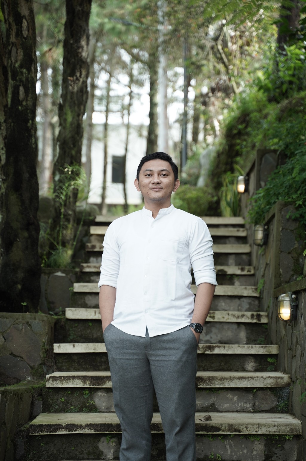 A winding road cuts through rocky terrain, surrounded by patches of green grass and illuminated by sunlight.