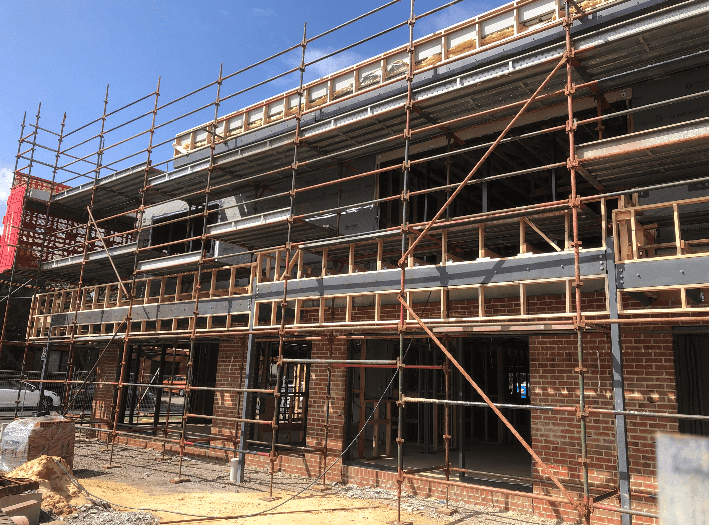Scaffolding on the exterior of a building clad with bricks in daytime by SubsQS NZ bank reporting