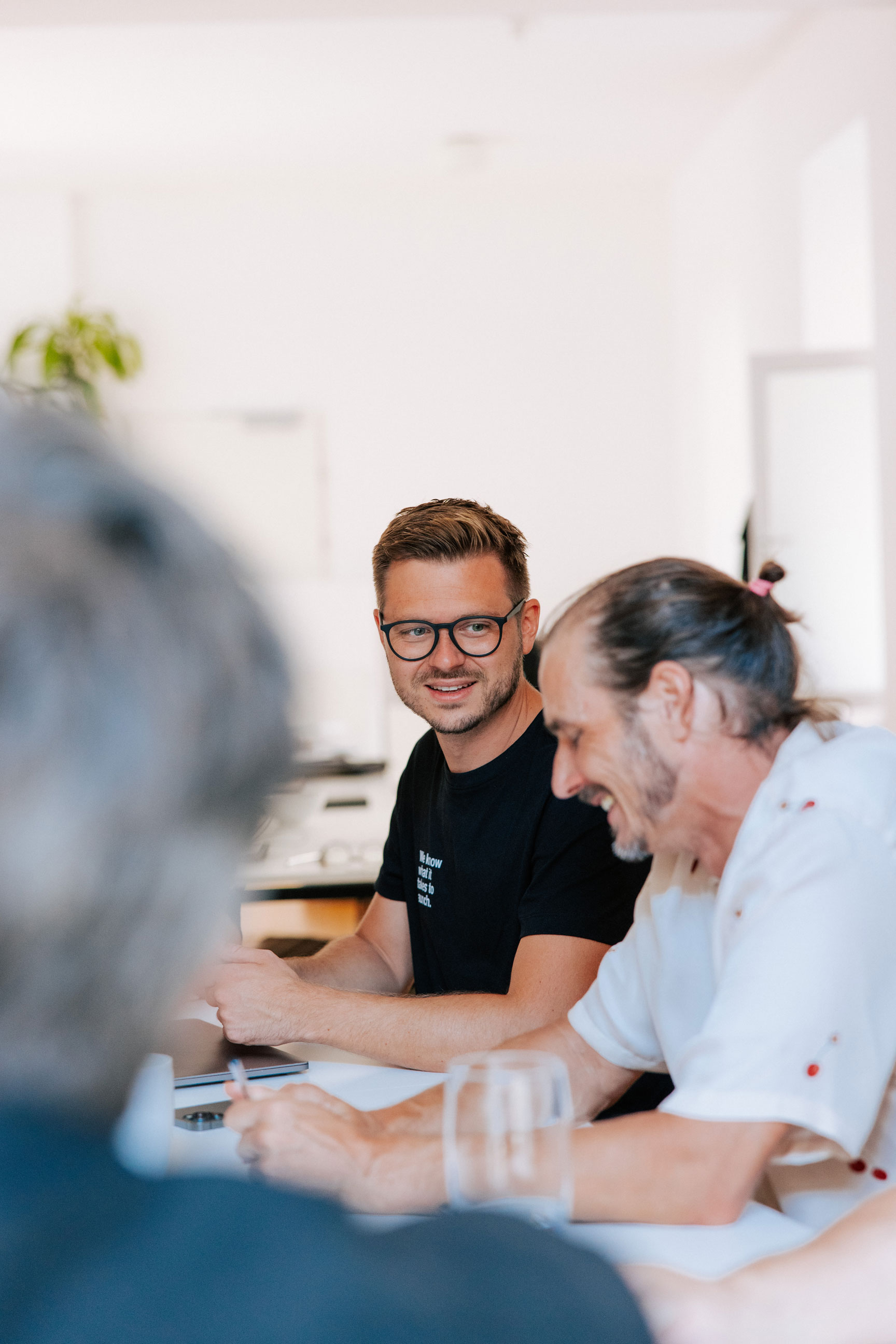 Two WRCO colleagues collaborate at a table in a bright office, smiling and reviewing work together.