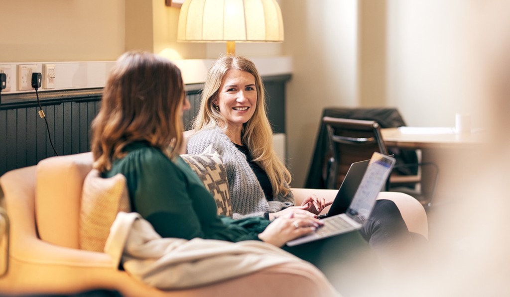 Two women chatting whilst sat on a sofa