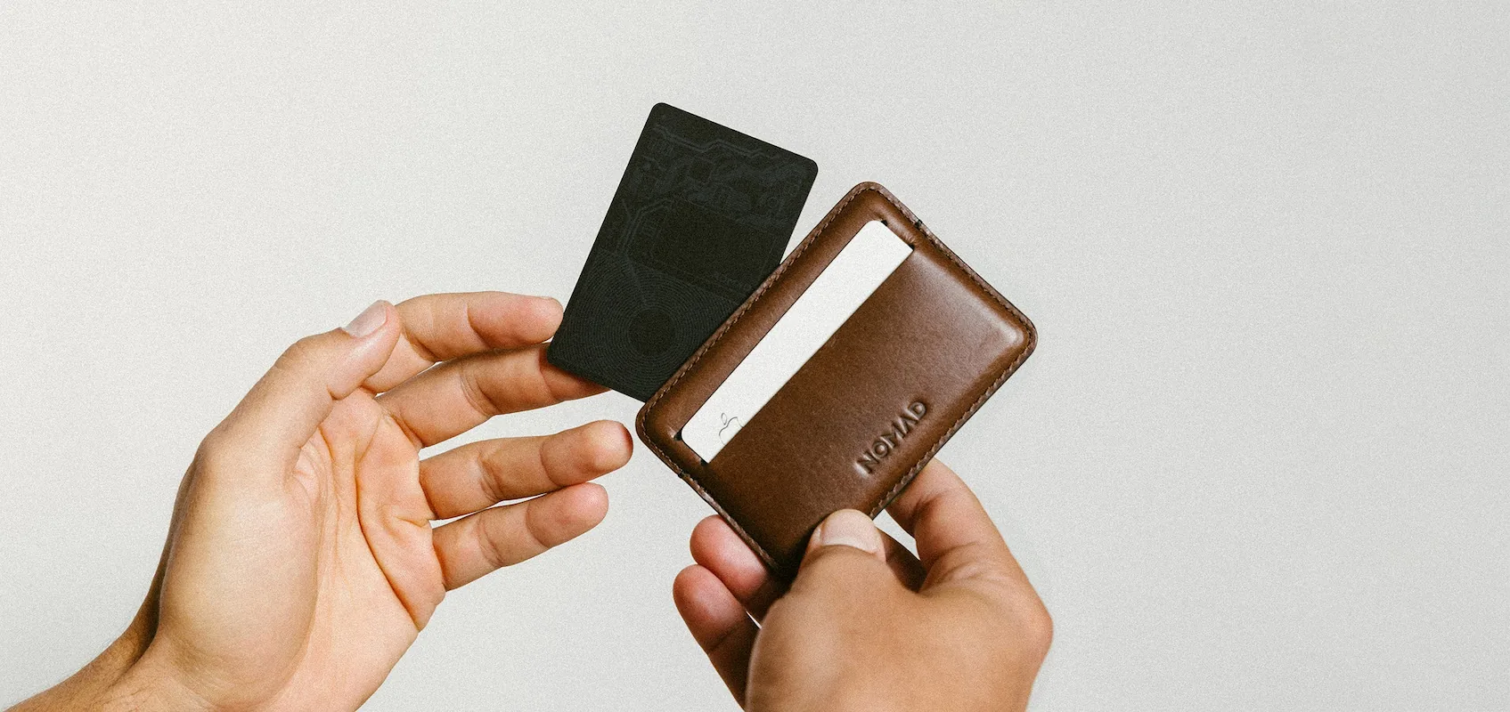 Person holding brown wallet and black tracking card
