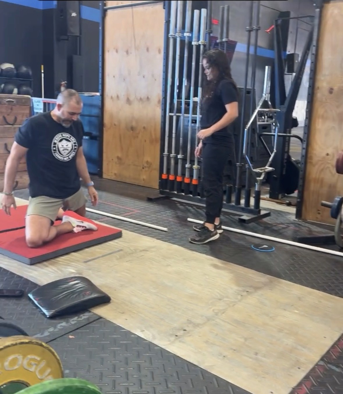 Black and white image of a gym wall with motivational fitness words like stamina, speed, accuracy, and kettlebells neatly lined up—symbolizing strength and discipline.