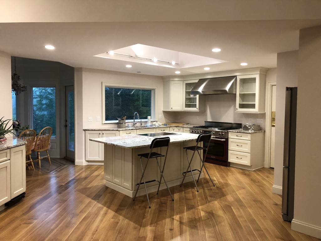 Modern custom kitchen with white cabinetry, large center island, hardwood floors, and recessed lighting by Casali Companies