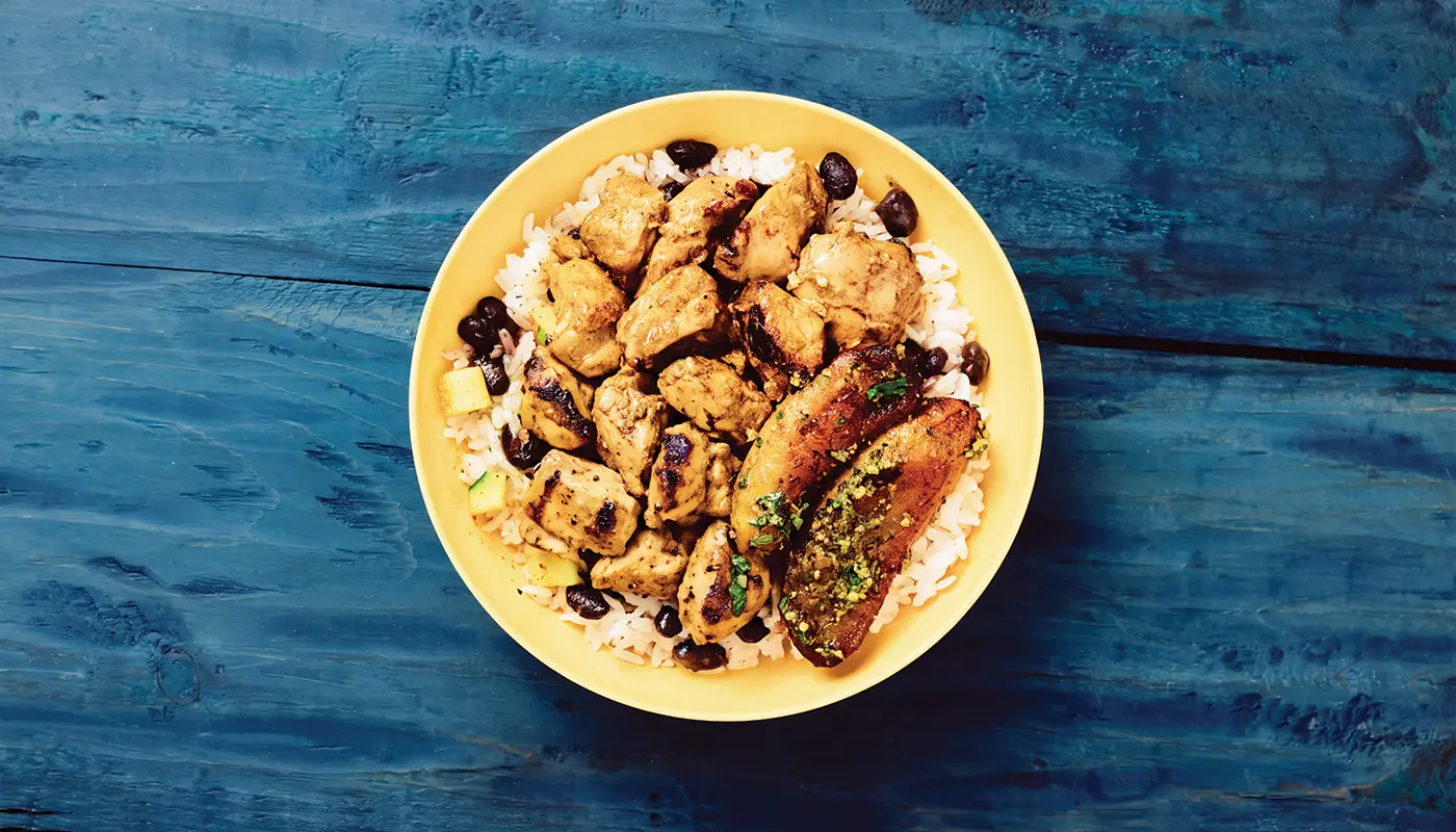 Overhead photograph of the Big Jerk bowl in a yellow bowl on blue wooden boards.
