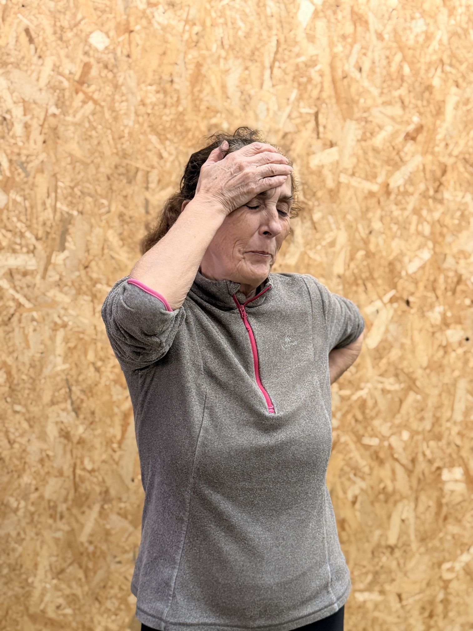 Woman with hand to forehead and eyes closed, appearing to have a headache.