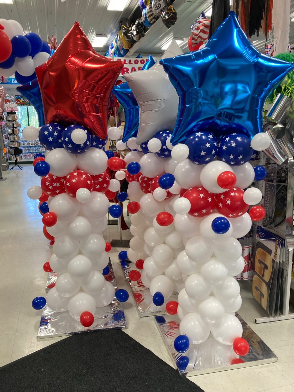 Pair of patriotic balloon columns with red, white, and blue balloons topped with large star-shaped balloons created by Be Bold Balloons