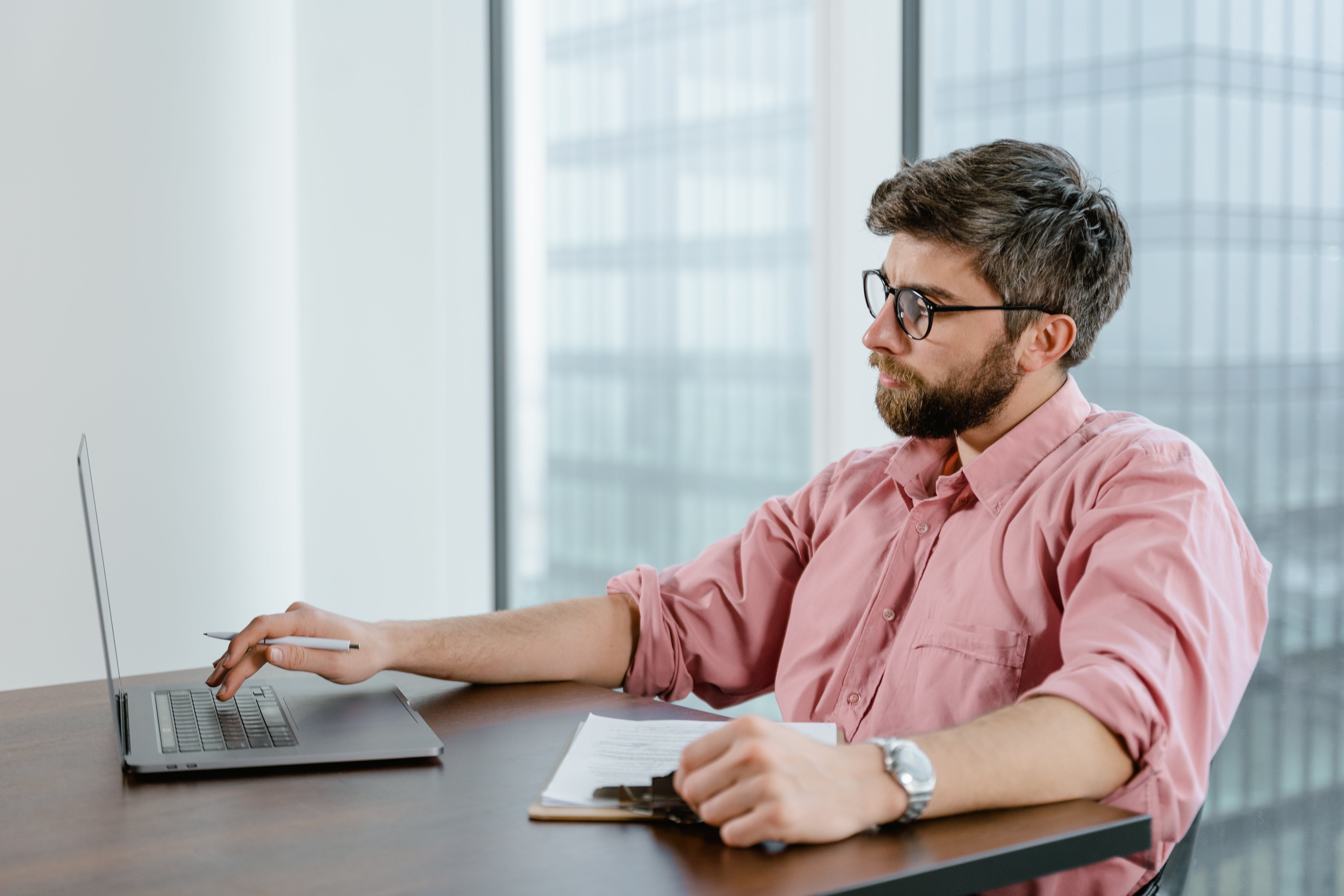 Mortgage advisor in pink dress shirt using laptop