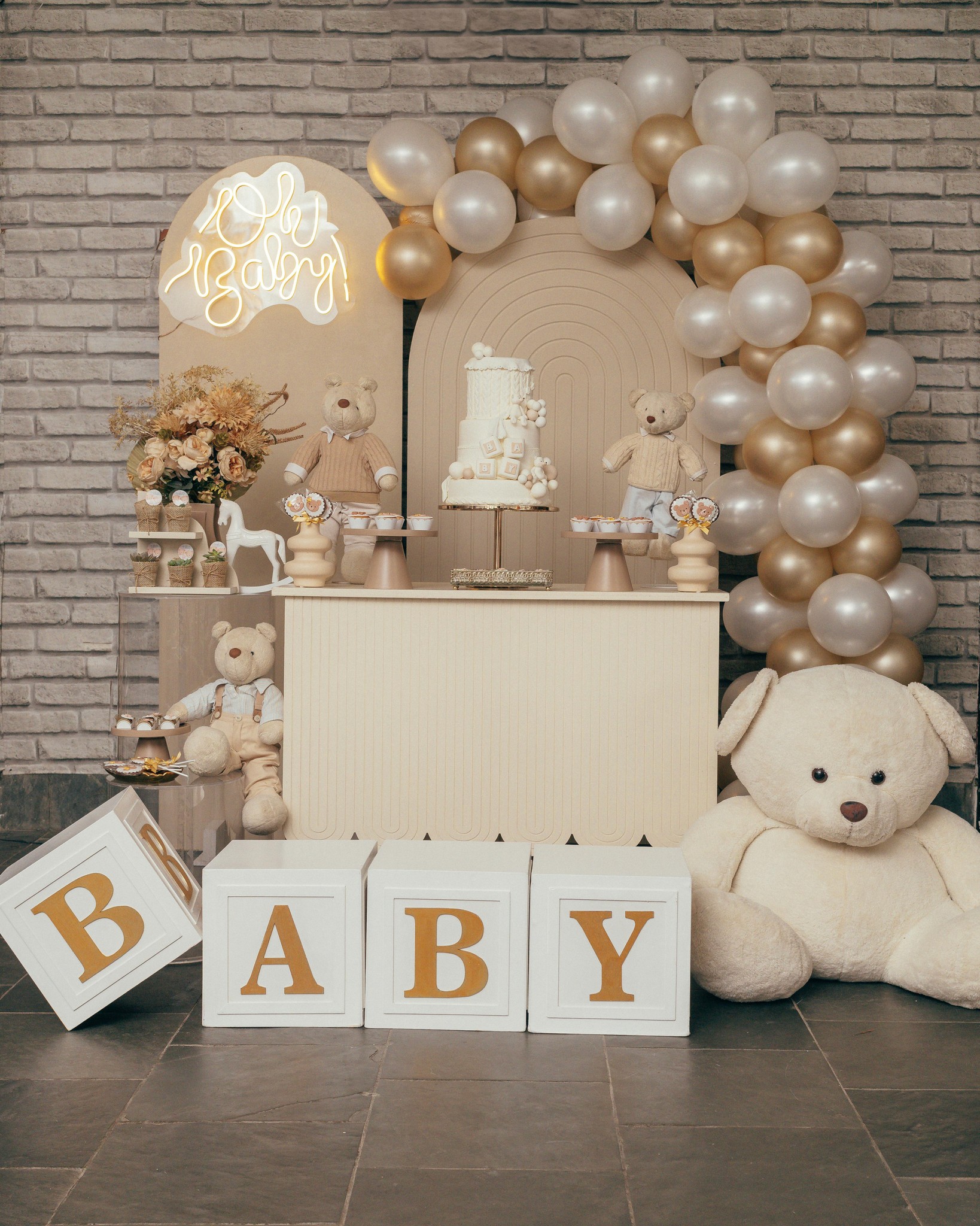 Neutral baby shower balloon backdrop with beige and white balloons, teddy bear, and BABY letter blocks arranged