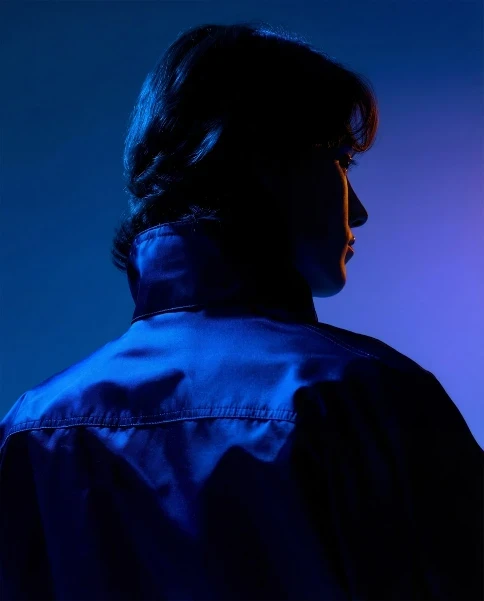 Portrait of a redhead woman in a black blazer with warm cinematic lighting in the background