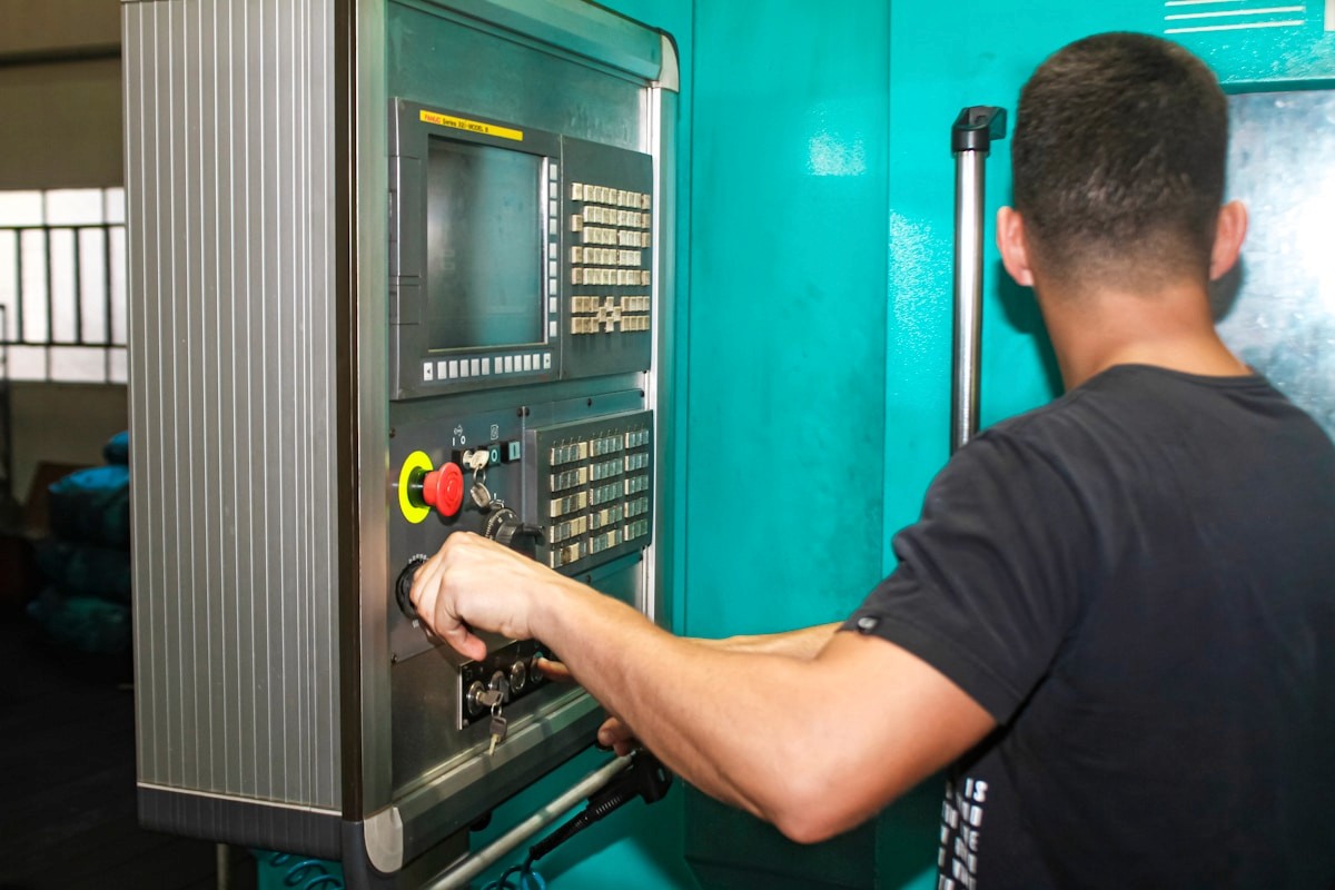 Indian factory worker operating a digital touchscreen control panel on a machine