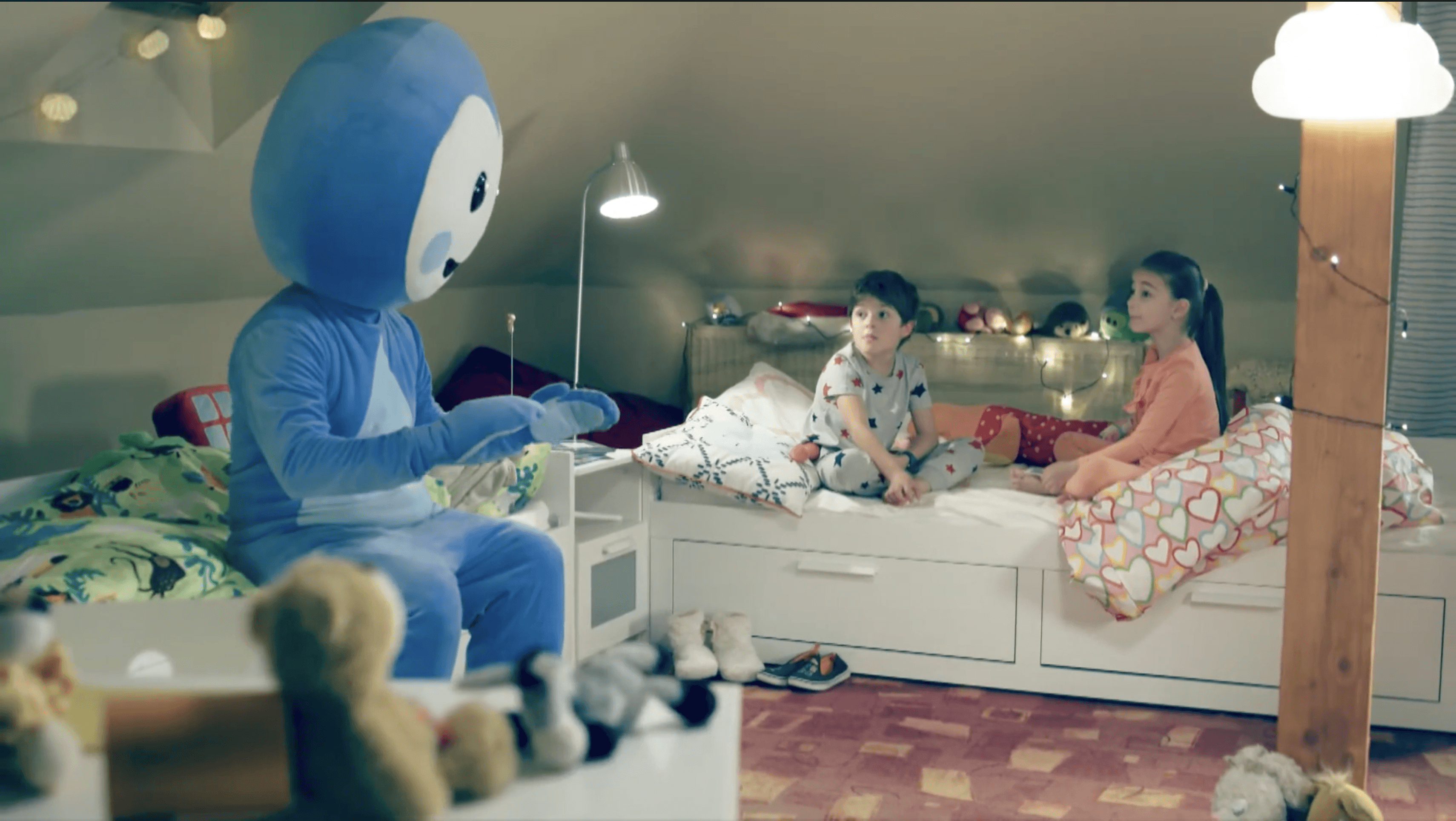 Cseppbarát kék kabalafigurája esti fényeknél beszélget a gyerekekkel