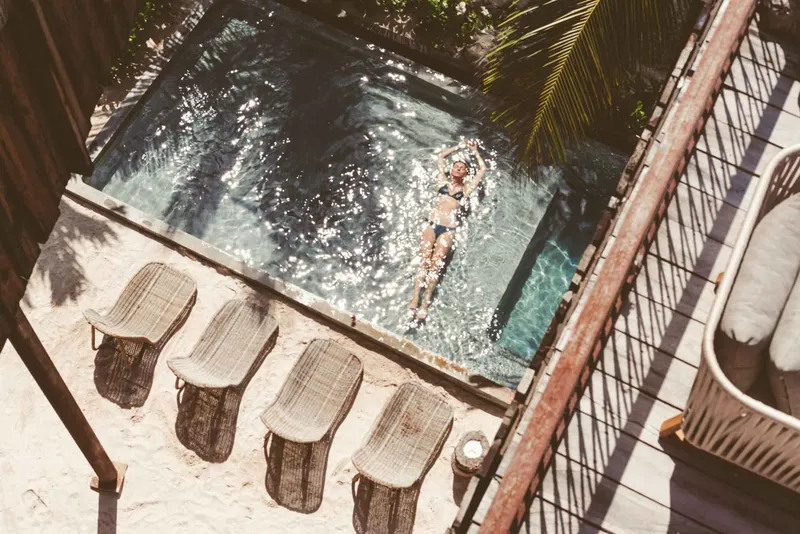 Pool area surrounded by jungle ambiance with loungers and tranquility at Be Tulum.
