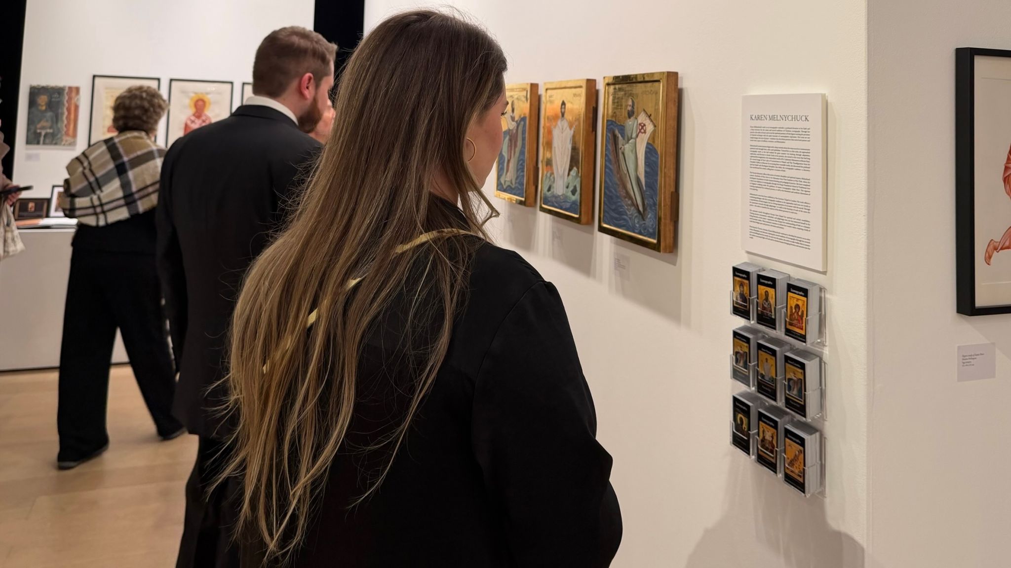 Alex and Tess observing Karen Melnychuck gallery exhibit, looking upon 3 gilded icons