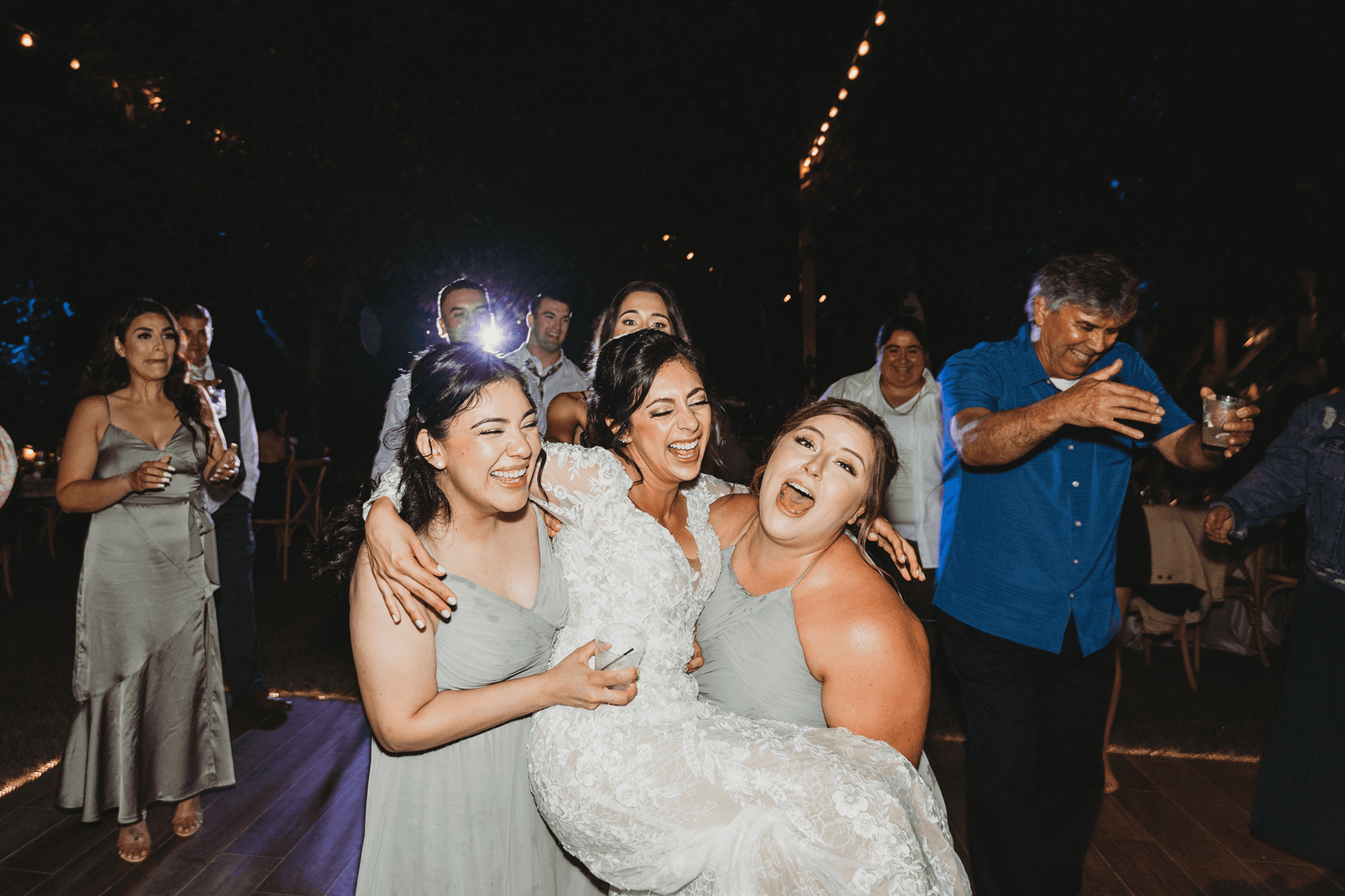 Bridesmaids laughing while lifting bride during reception